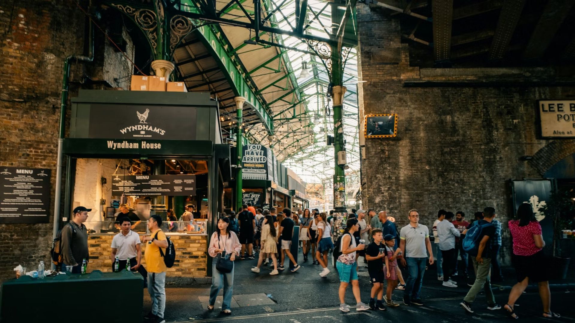 People stroll through a bustling market filled with shops and vibrant food stalls.