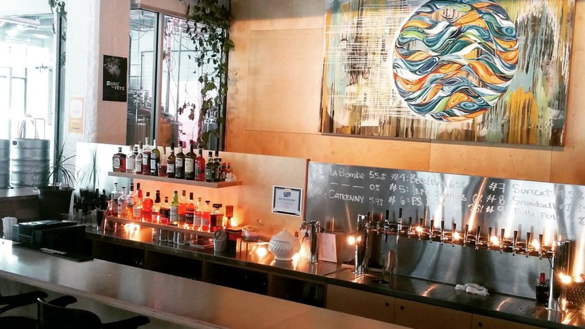 Inside a bar, a large artwork hangs on the wall, adding character to the space.