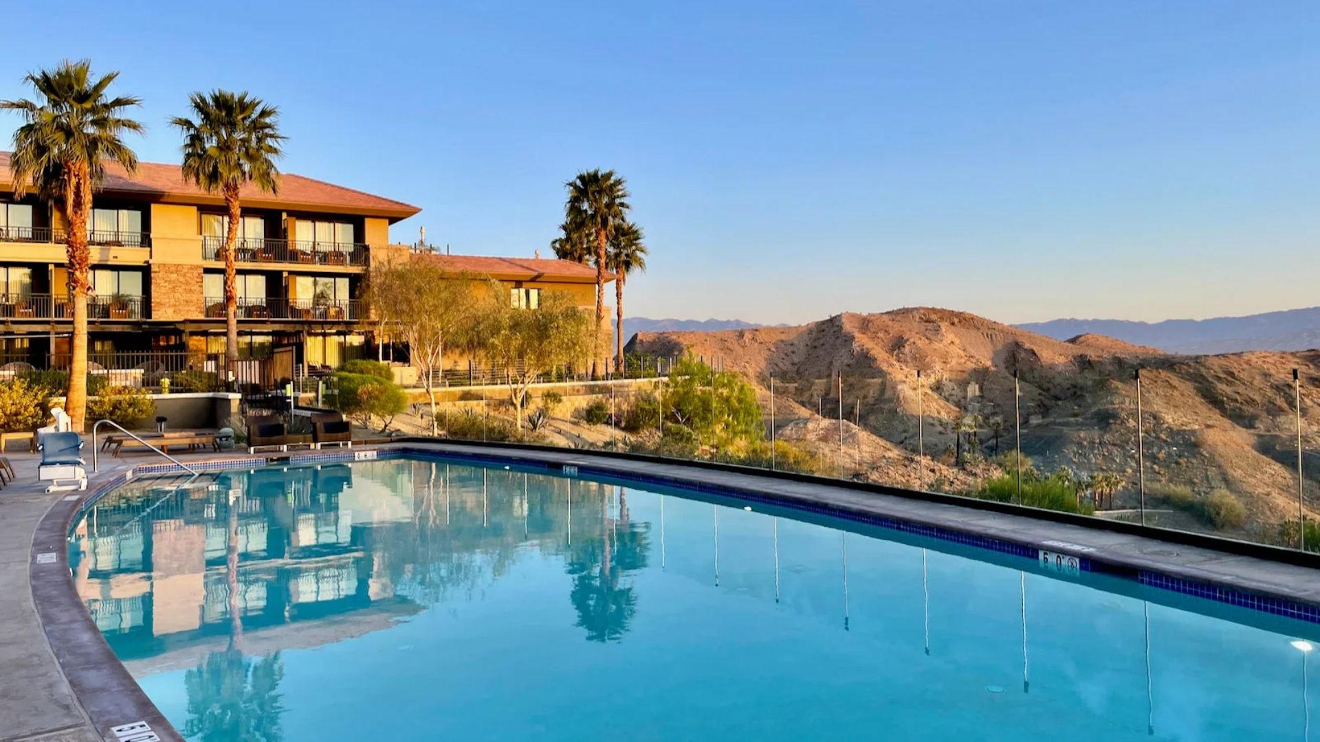A serene pool surrounded by palm trees at the Palm Springs resort, inviting relaxation under the clear blue sky.