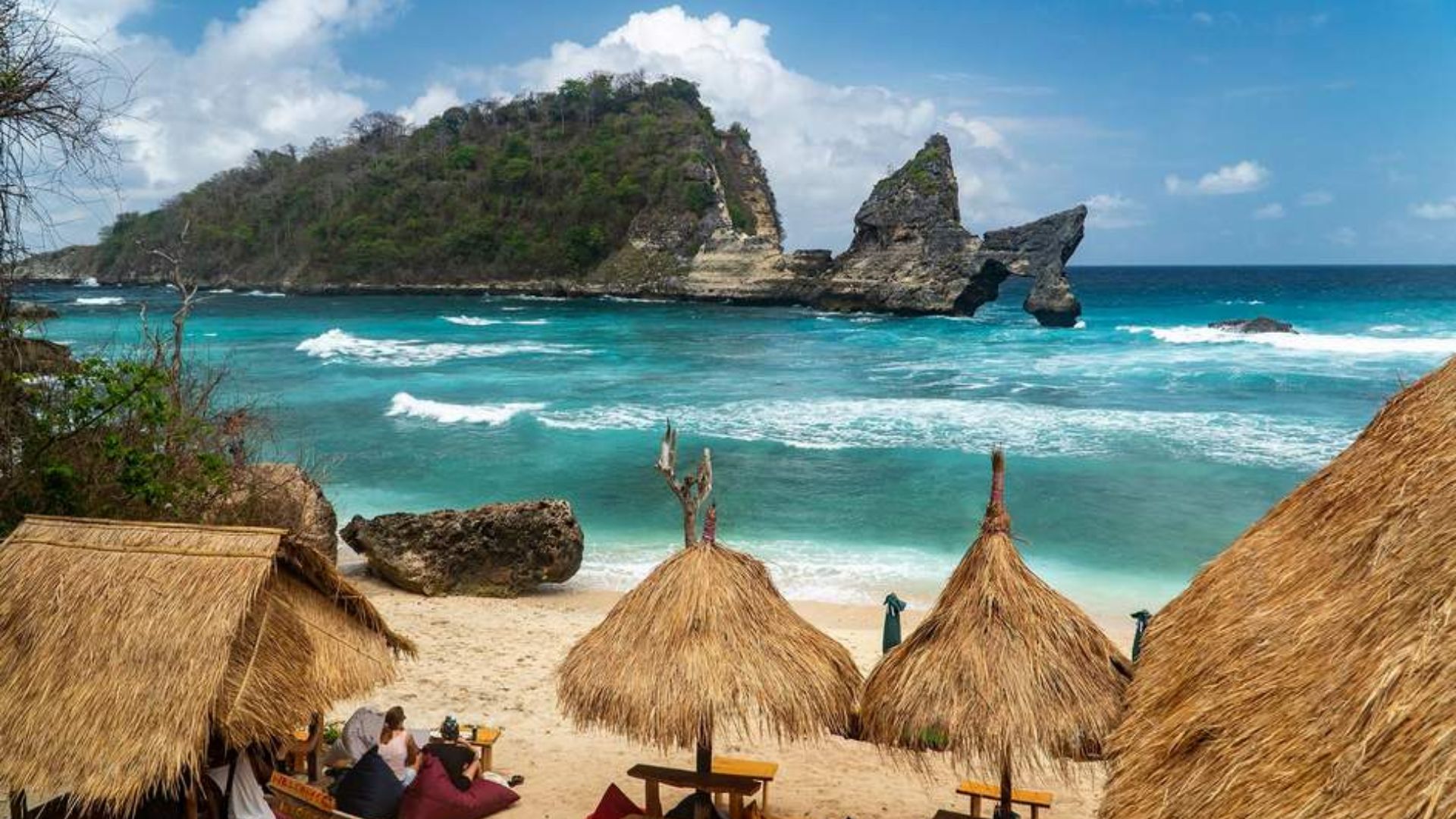 A serene beach scene featuring thatched huts with a clear view of the ocean in the background.