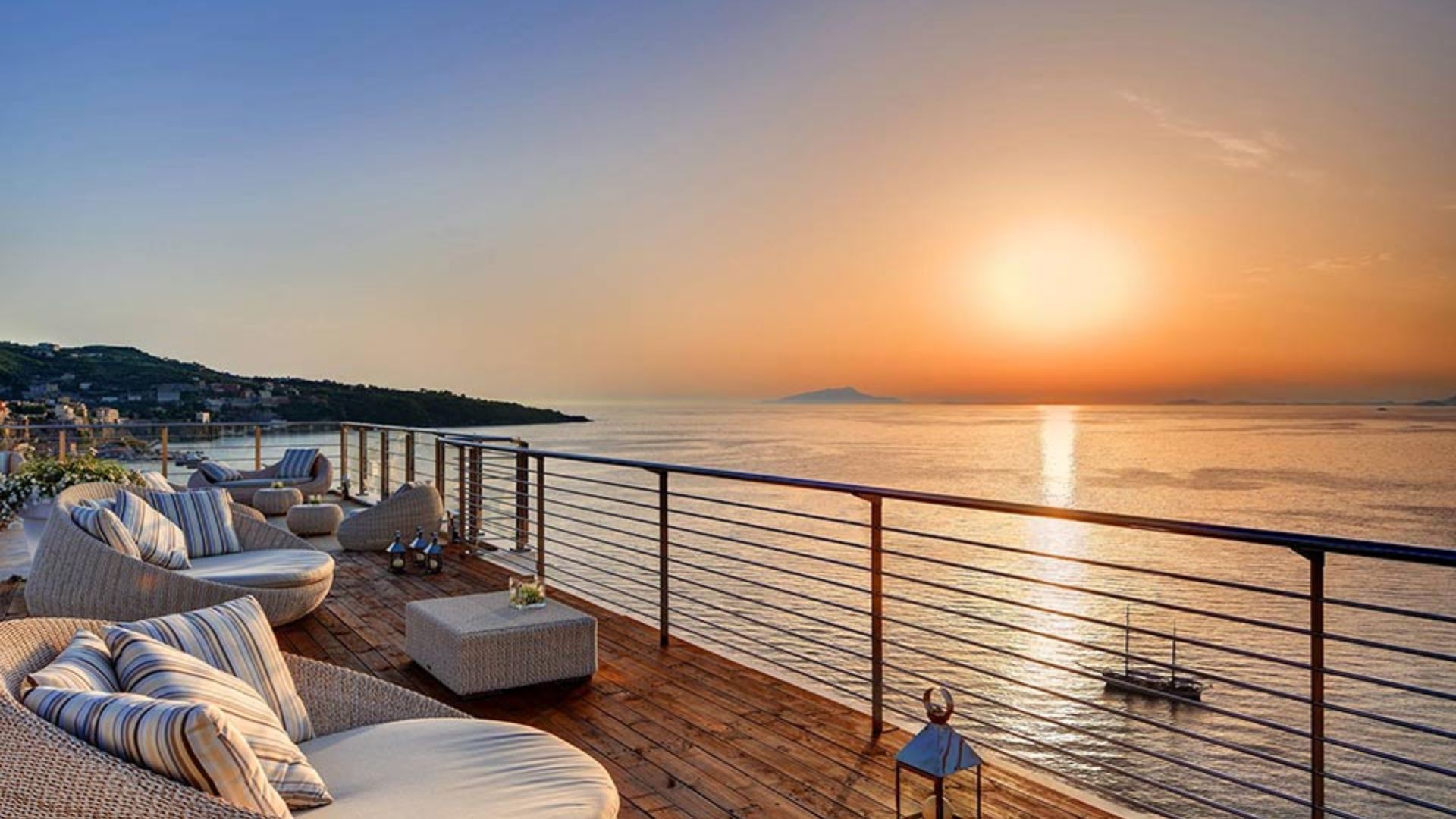 A balcony with a view of the ocean at sunset, showcasing vibrant colors reflecting on the water.