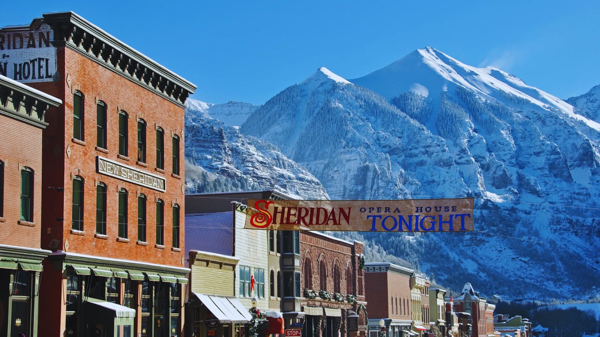 Urban street scene featuring buildings, with a stunning mountain range visible in the background.