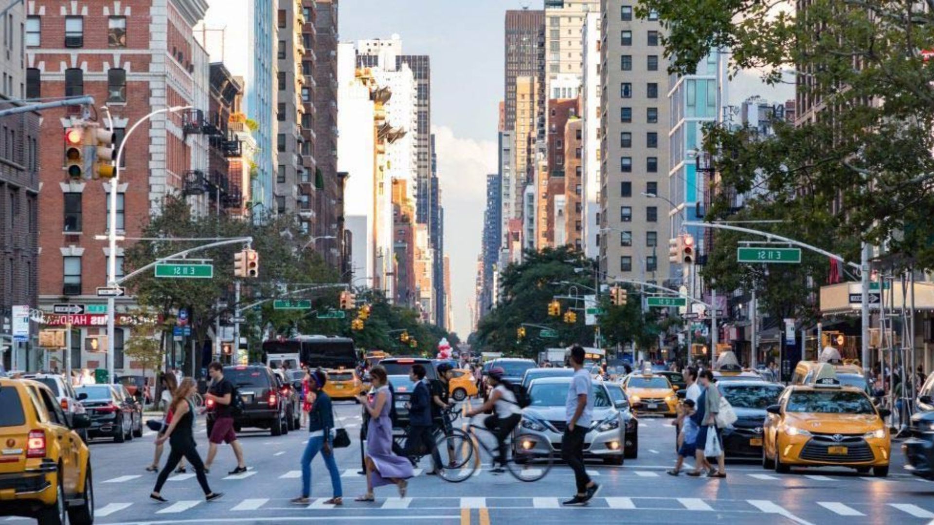 A crowded urban street scene with numerous people crossing the road.