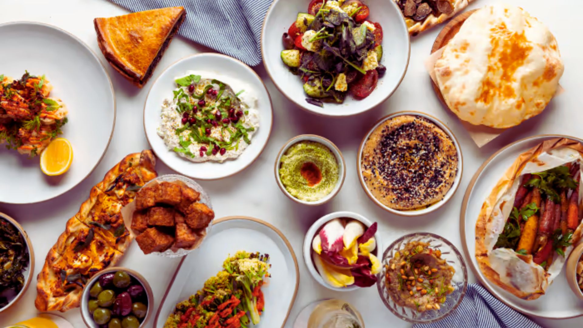 A table filled with a variety of dishes, including fruits, vegetables, meats, and desserts, showcasing diverse cuisines.