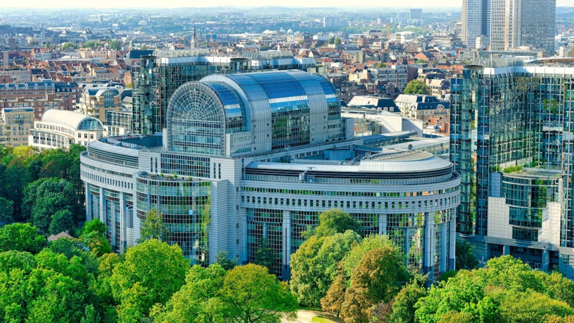 European Parliament building in Brussels, Belgium, showcasing modern architecture and the European flag flying outside.