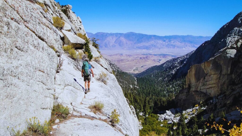 A man hiking up a steep mountainside, focused on his ascent against a rugged landscape.