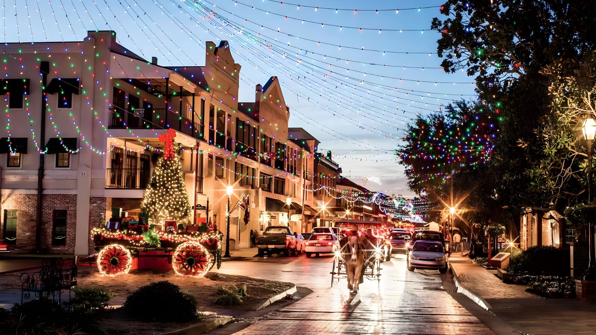 A festive street adorned with Christmas lights, featuring a horse-drawn carriage passing through the illuminated scene.