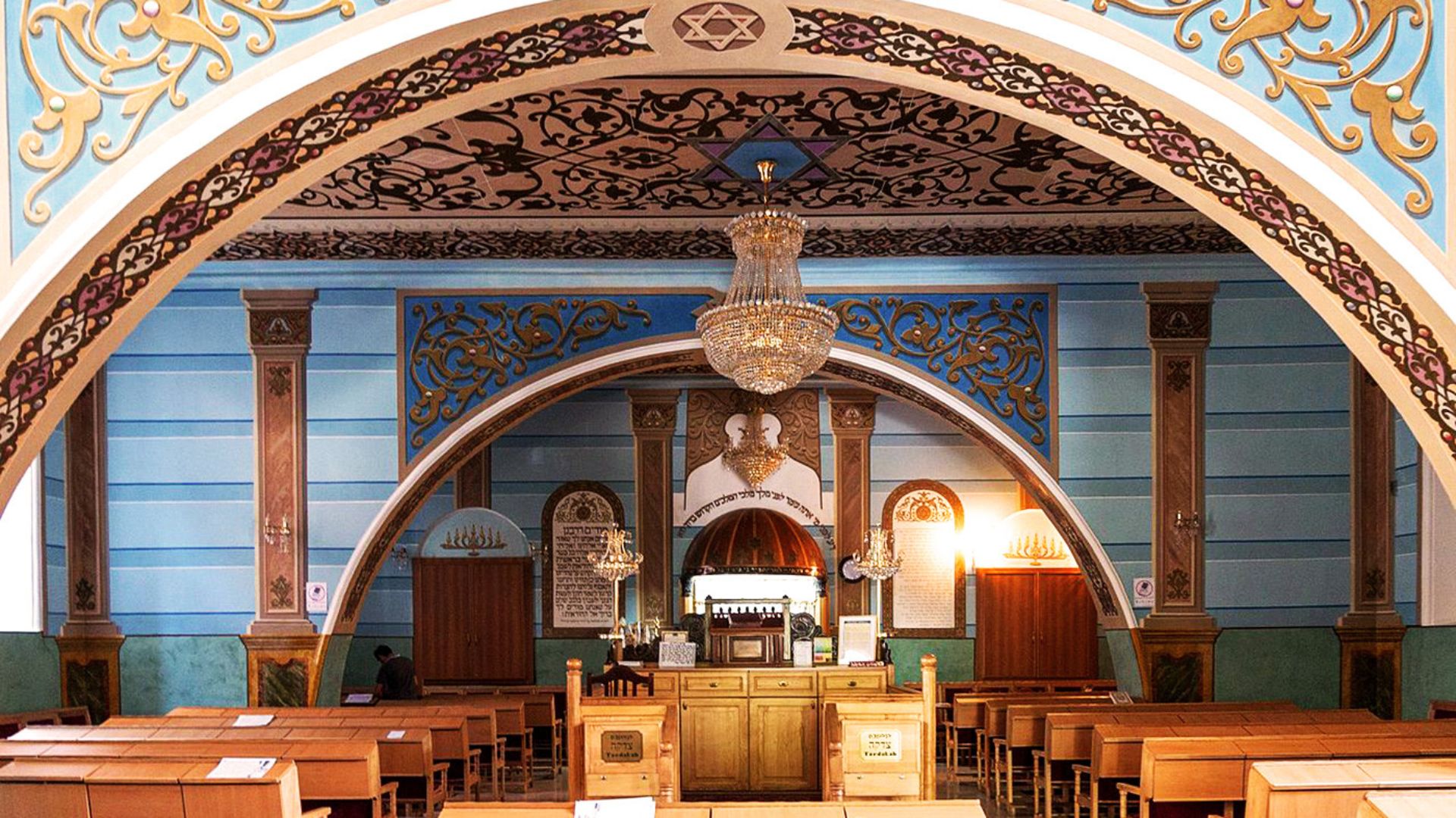 Church interior showcasing intricate arches and a stunning chandelier hanging from the ceiling.