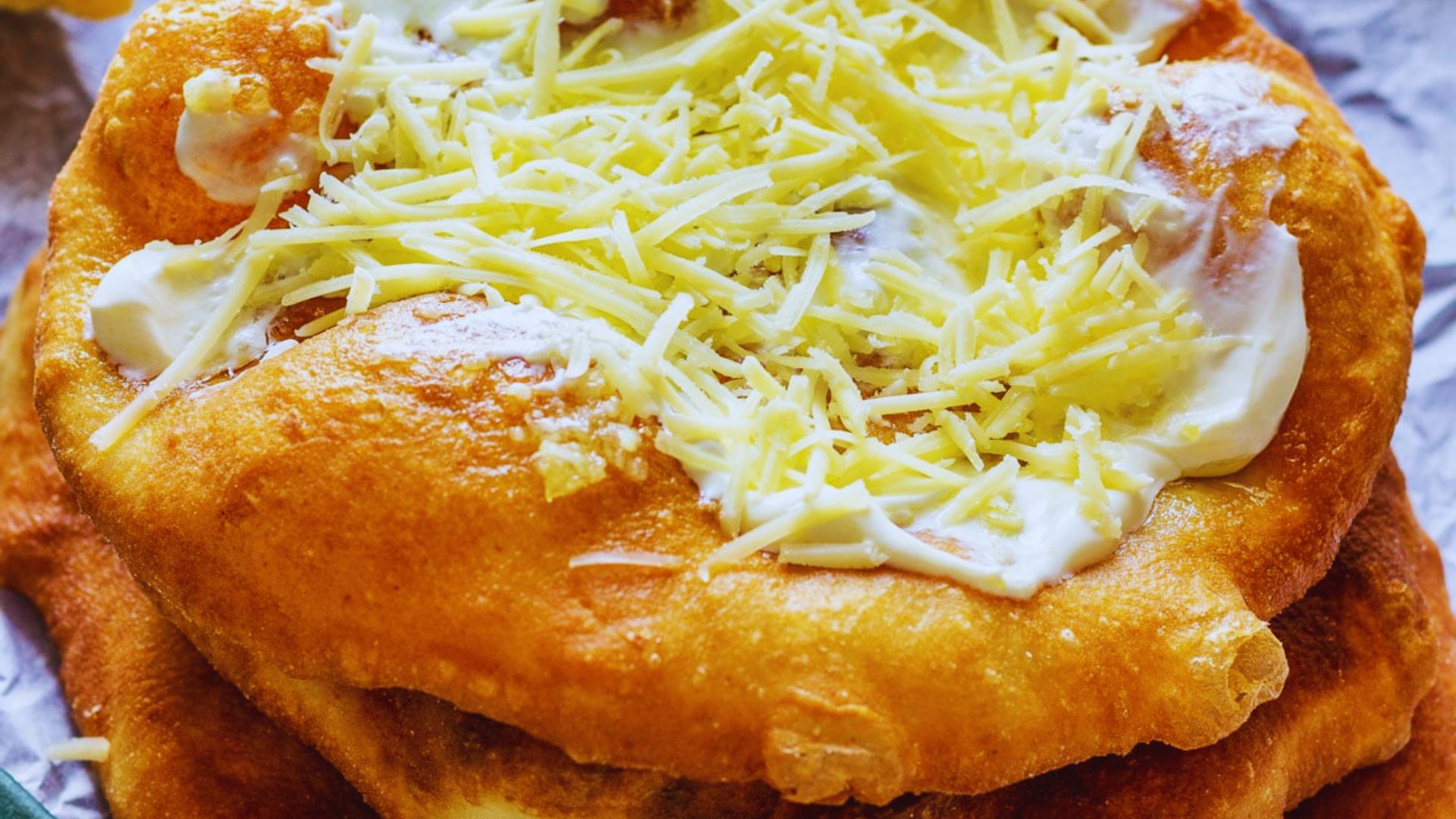 A colorful pile of food topped with melted cheese and dollops of sour cream, showcasing a hearty meal.