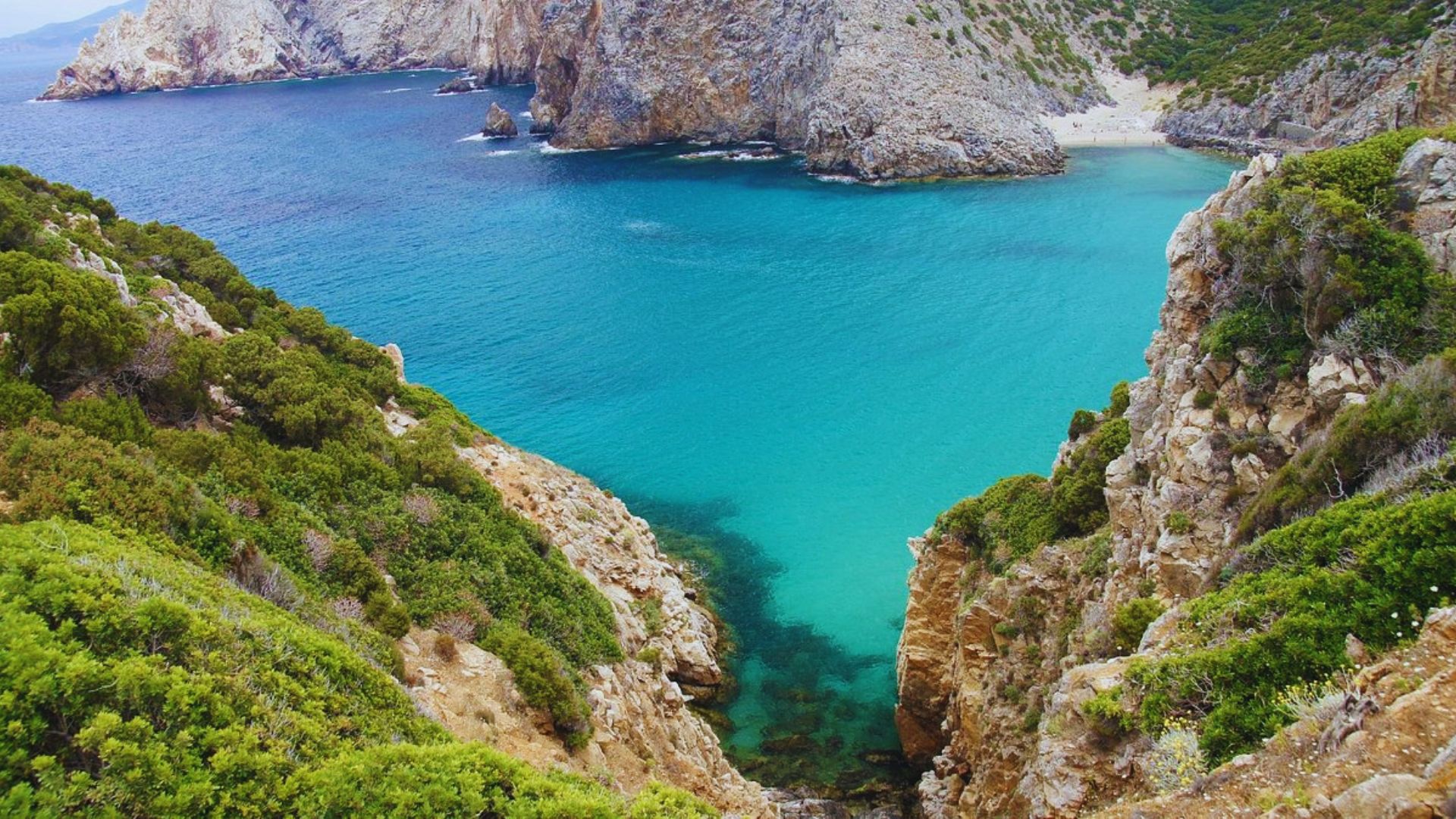 A stunning coastal view of turquoise waters surrounded by rugged cliffs and green foliage. The scene conveys a serene and natural beauty.