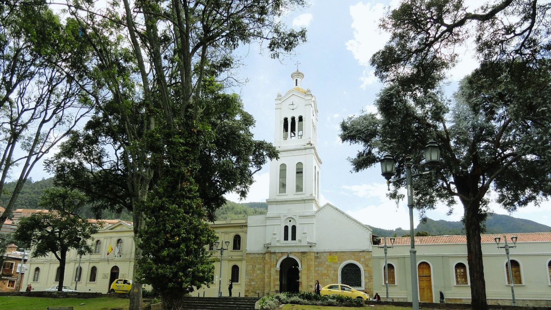 A church with a tall steeple surrounded by lush green trees in the background.