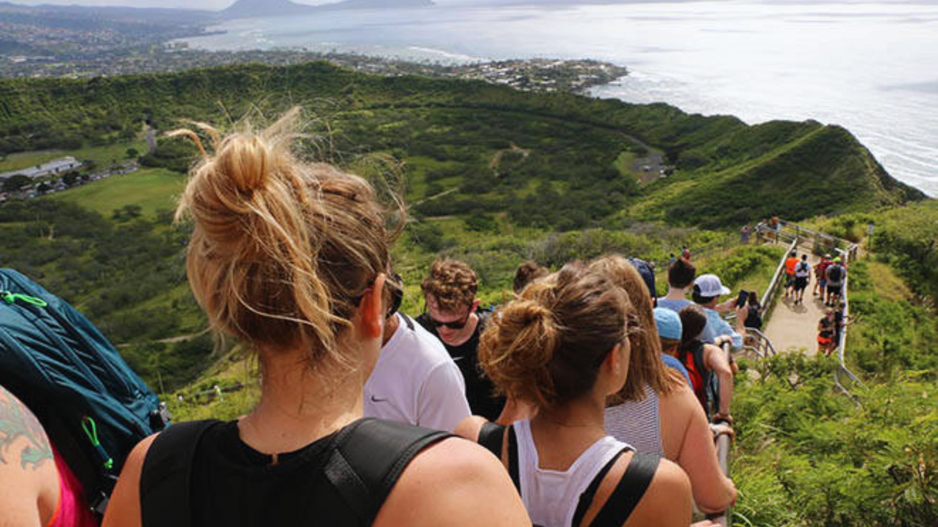 A group of hikers ascending a mountain trail, surrounded by rocky terrain and greenery.