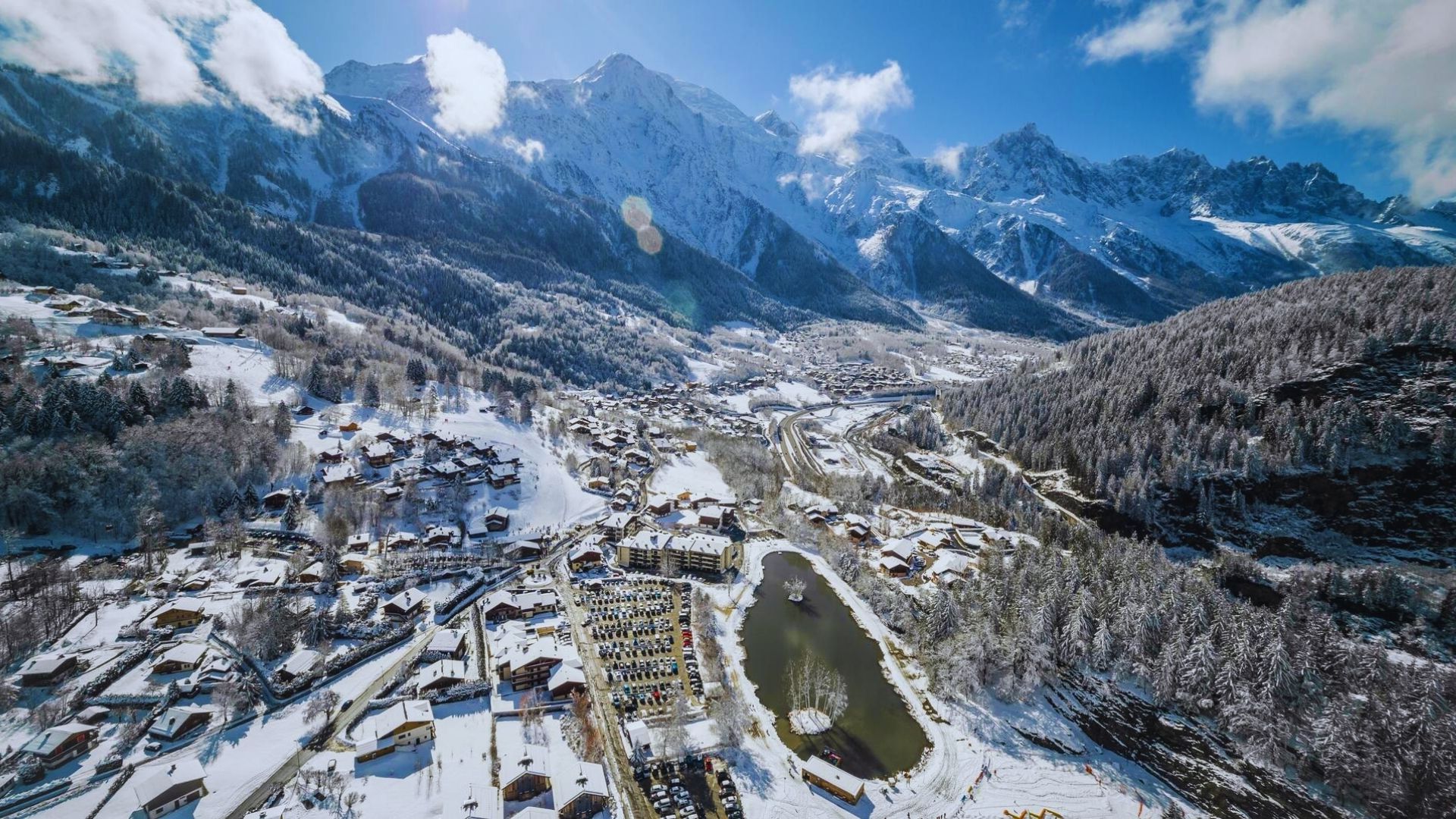 Aerial view of a mountain village, showcasing houses nestled among lush greenery and rugged peaks.