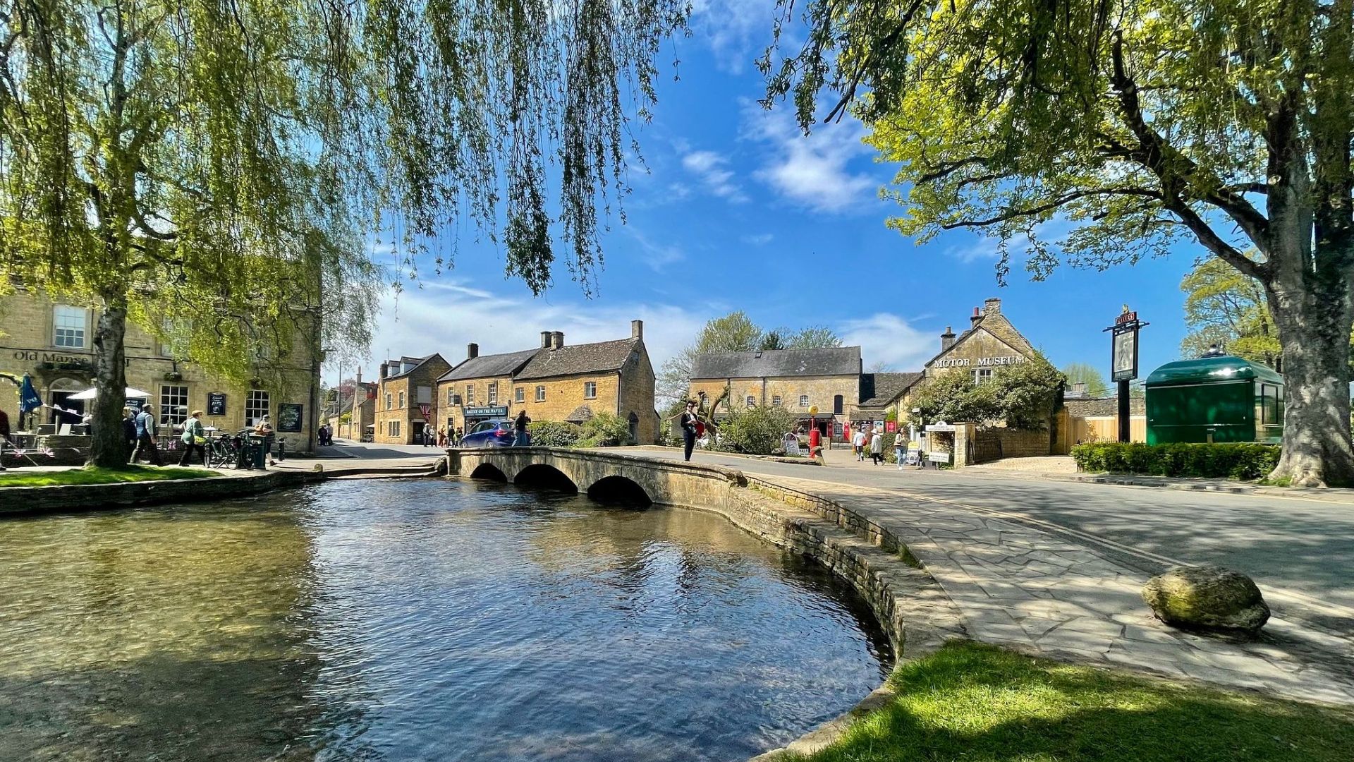 A serene river winds through a small town, bordered by houses and greenery, showcasing a tranquil community setting.
