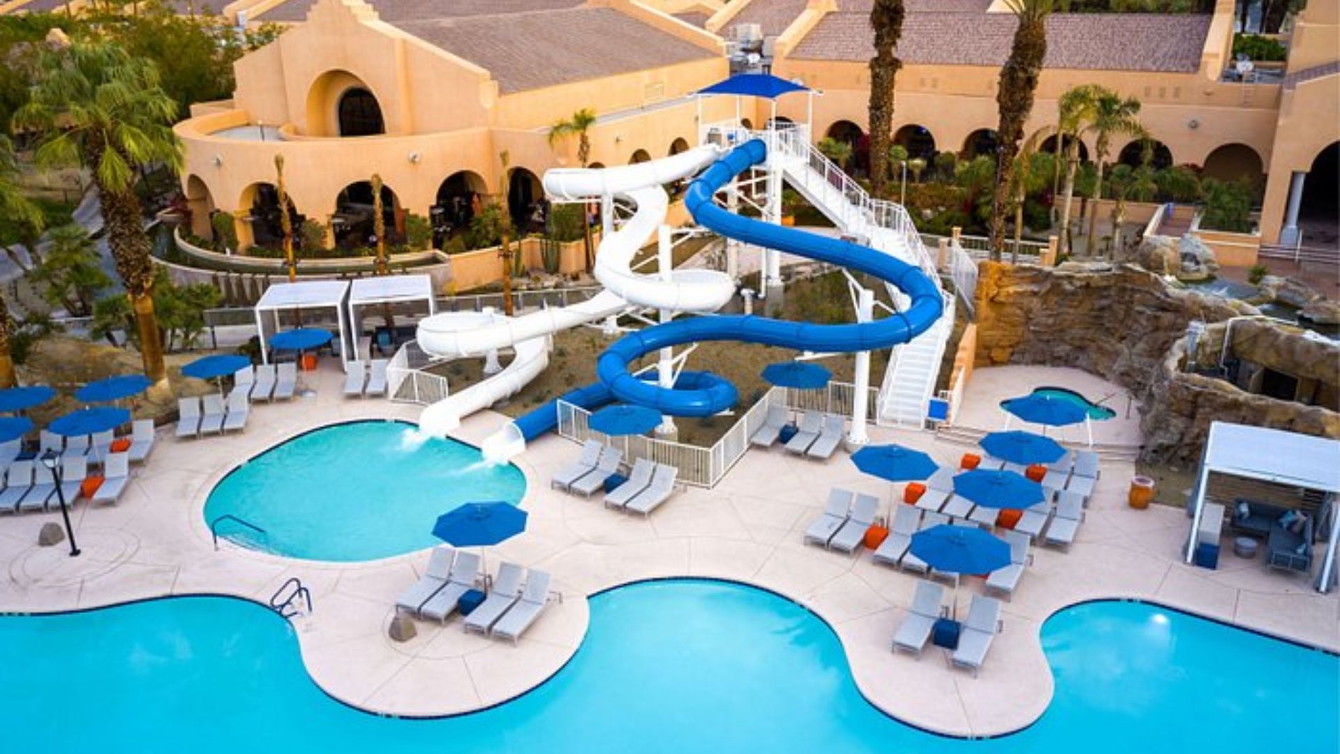A swimming pool featuring a water slide and several lounge chairs arranged around the edge.