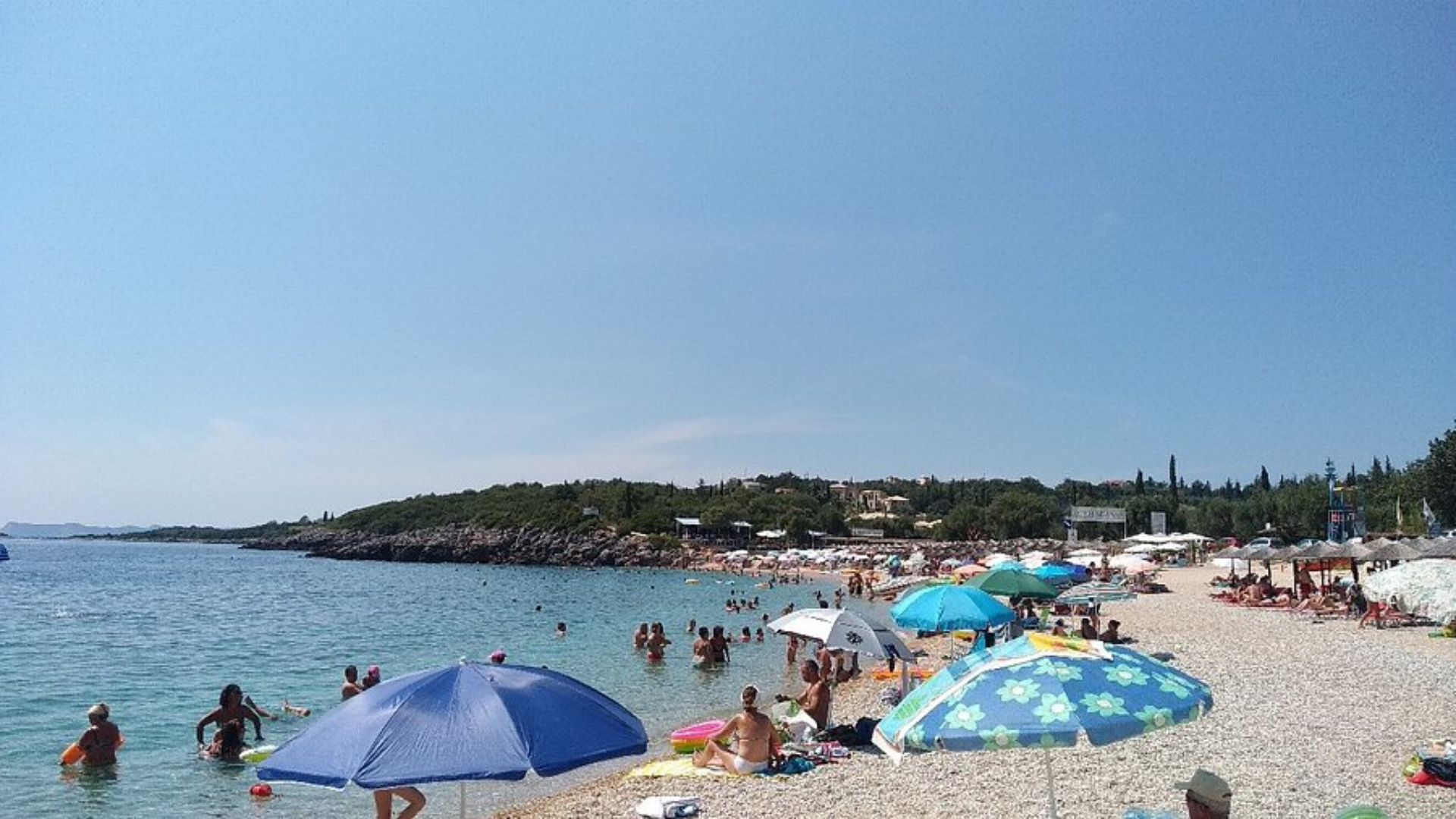 A crowded beach filled with people relaxing under colorful umbrellas on a sunny day.