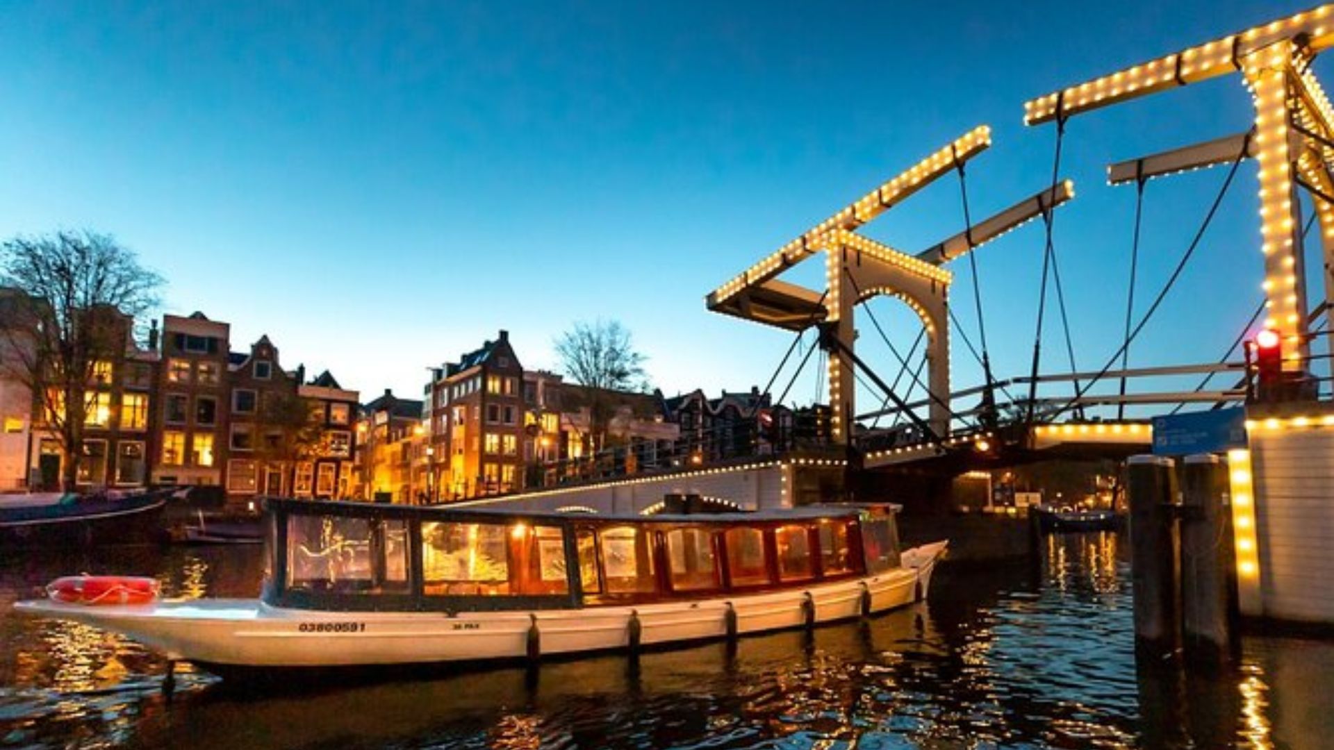 A boat glides beneath a bridge, illuminated by moonlight, creating a serene night scene.