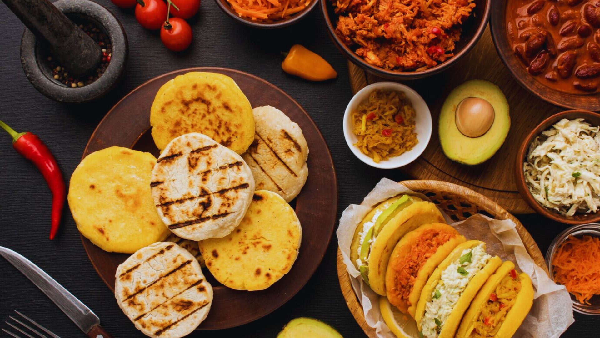 A colorful spread of Mexican food featuring tortillas, beans, and various fresh ingredients arranged on a plate.