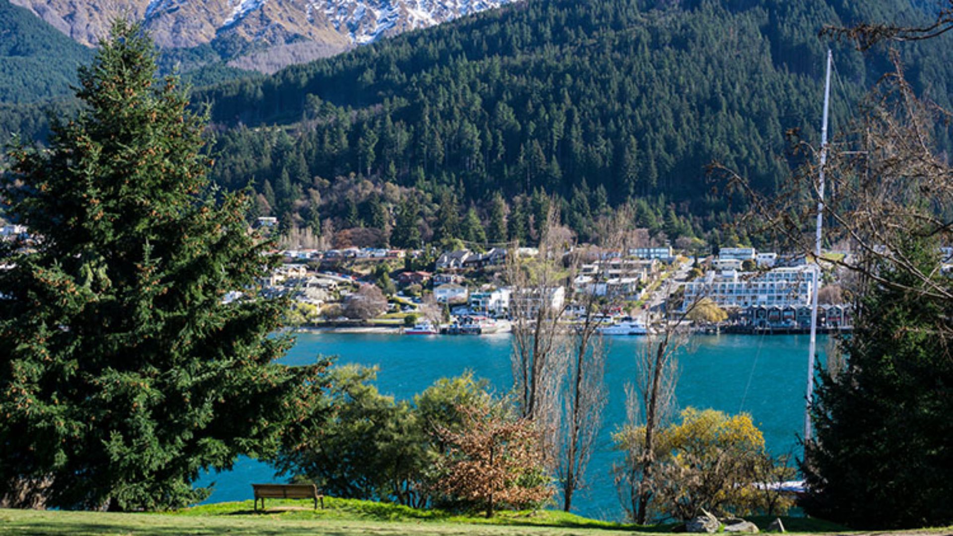Scenic view of a tranquil lake surrounded by majestic mountains in Queenstown, New Zealand.