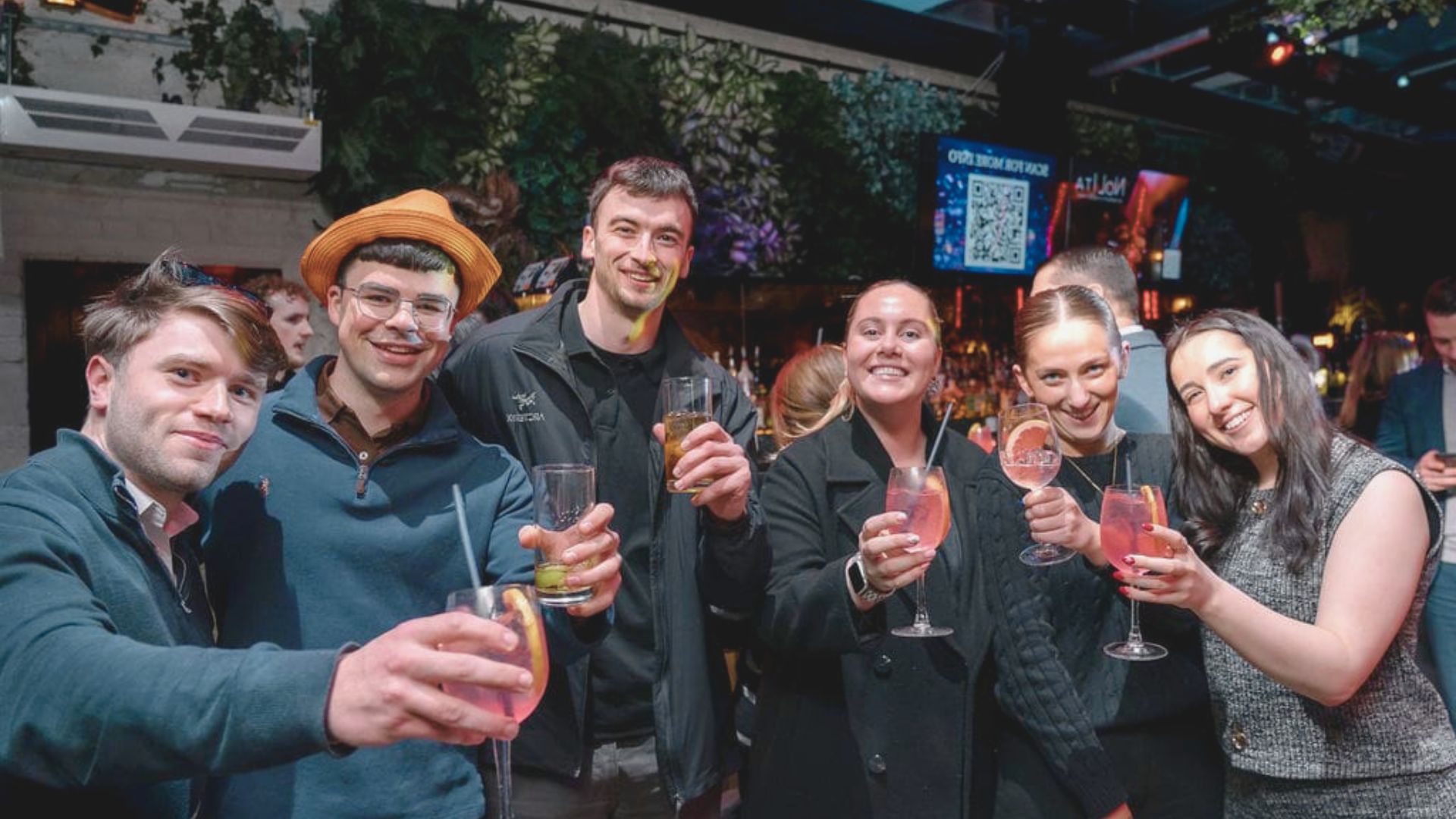 Friends celebrating at a party, each holding a drink and engaging in conversation.