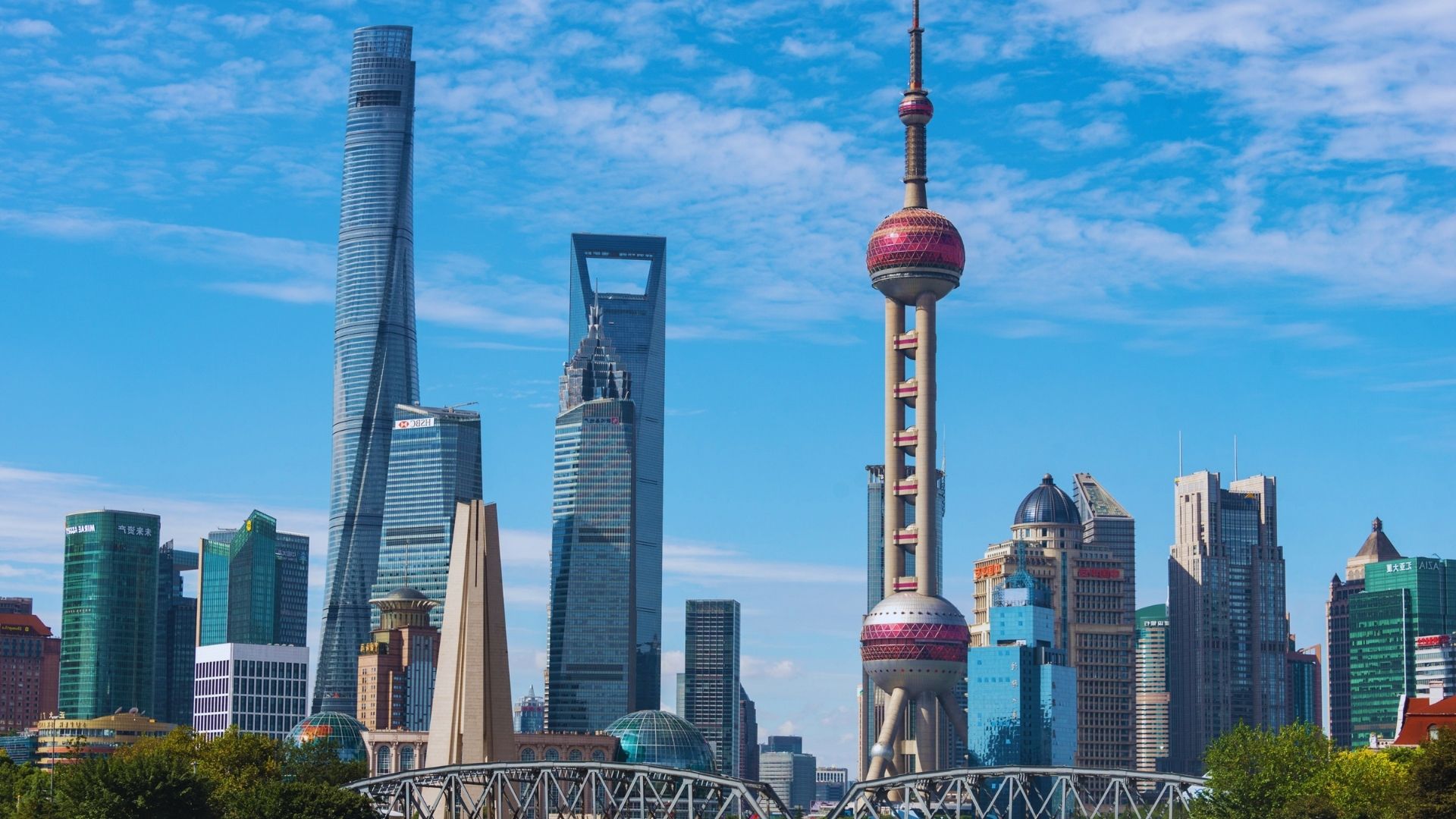 The Shanghai skyline viewed from a boat, showcasing modern skyscrapers against a clear blue sky.