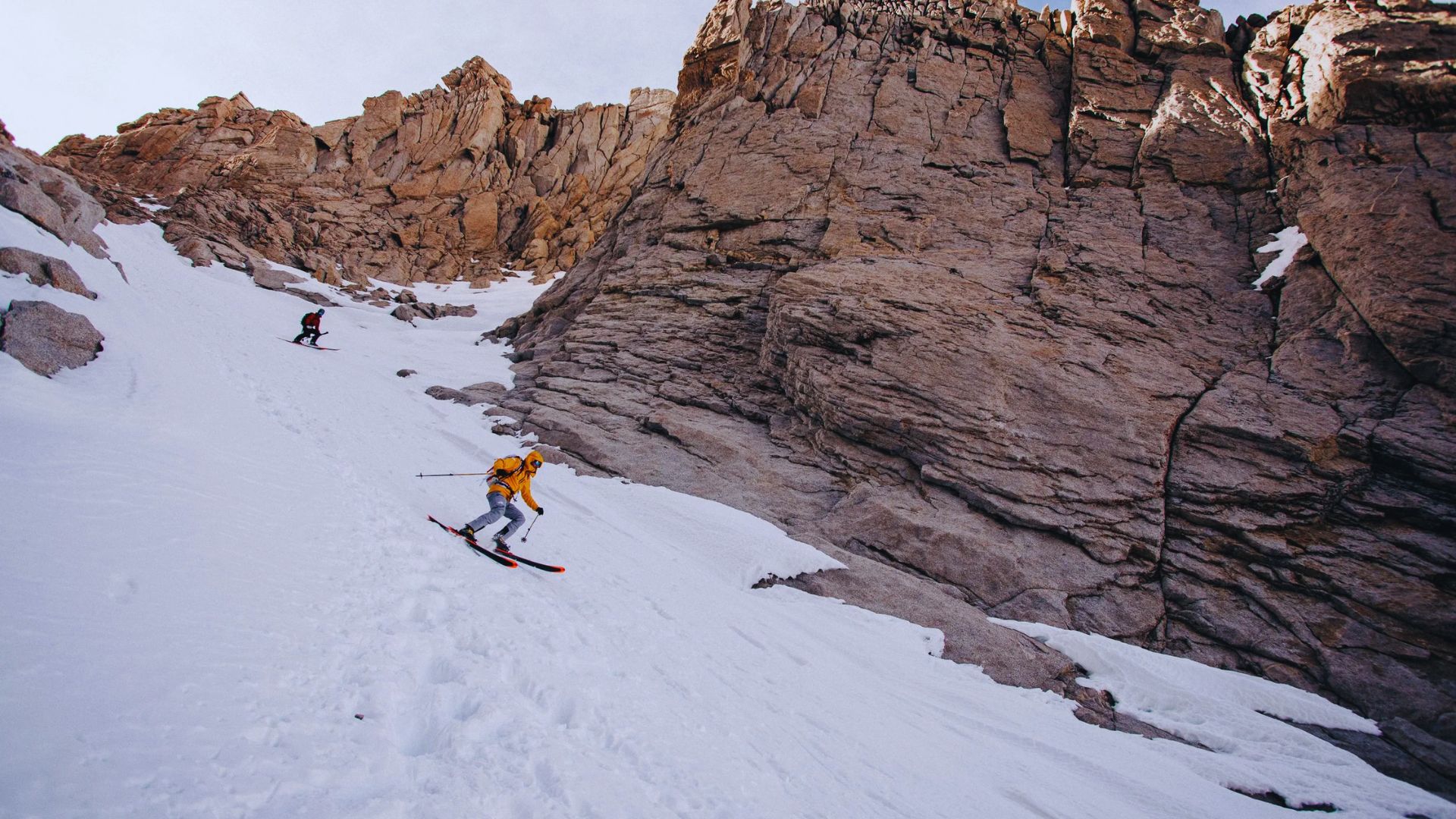 A man skiing down a steep mountain slope, showcasing his skill and balance against a snowy backdrop.