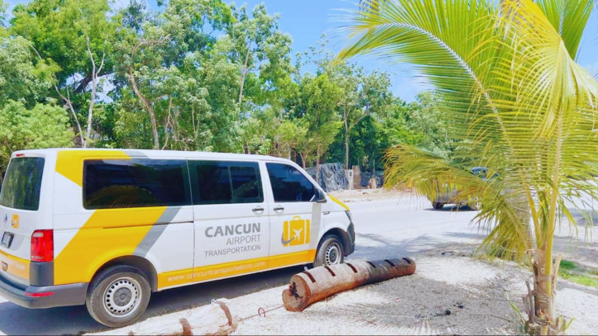 A van parked on the side of a road, surrounded by greenery and a clear blue sky.