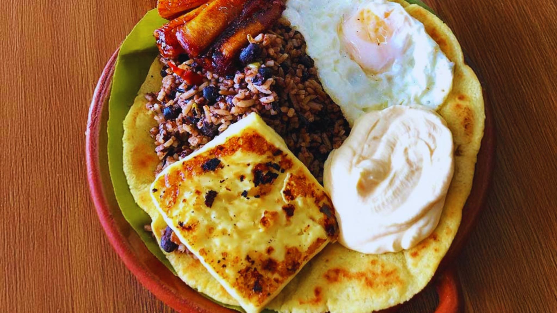 A plate featuring a tortilla topped with scrambled eggs and a side of black beans.