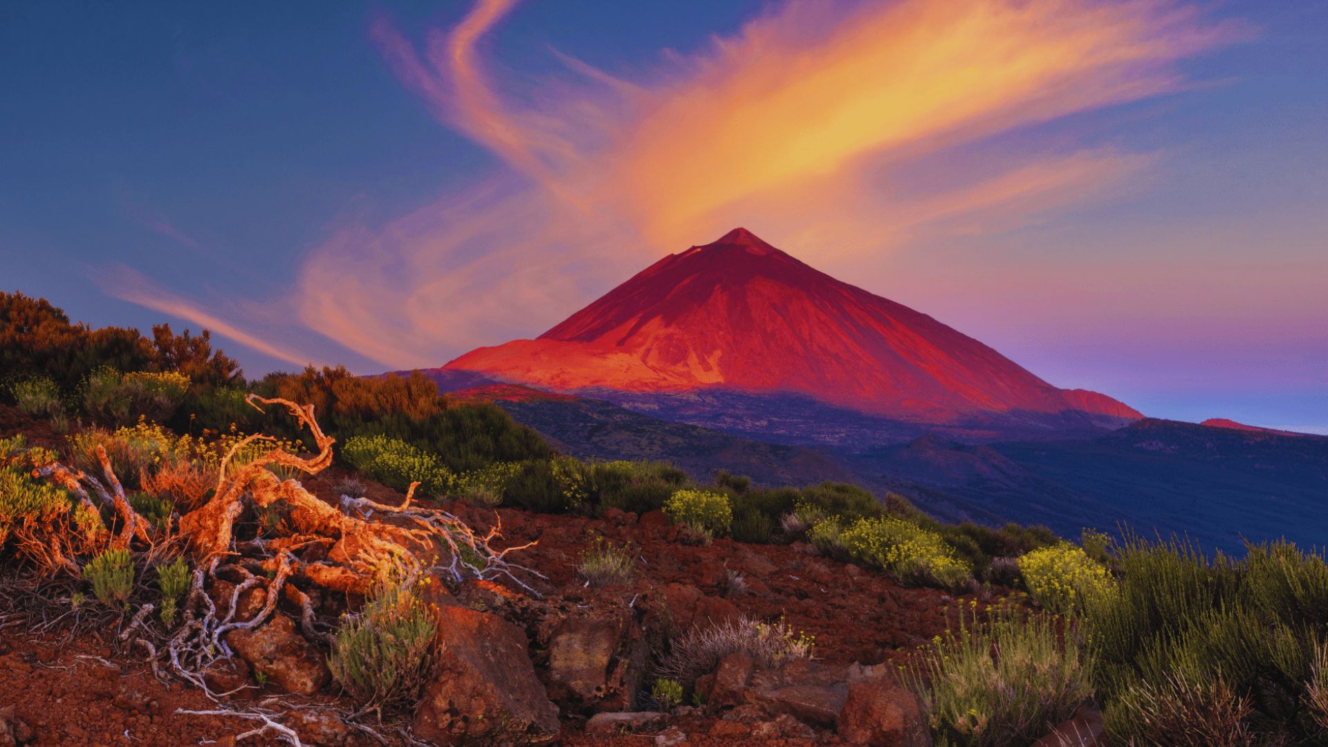 A mountain silhouetted against a sky glowing red at sunset, creating a dramatic and striking landscape.