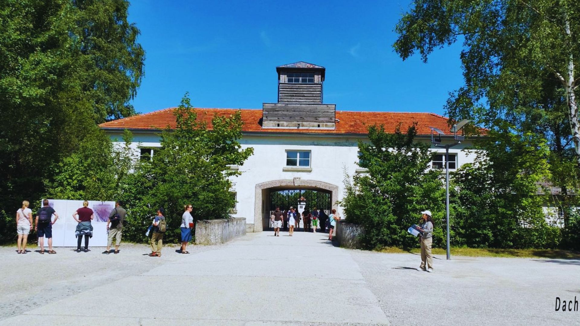 A group of people stands outside a building featuring a prominent clock tower.