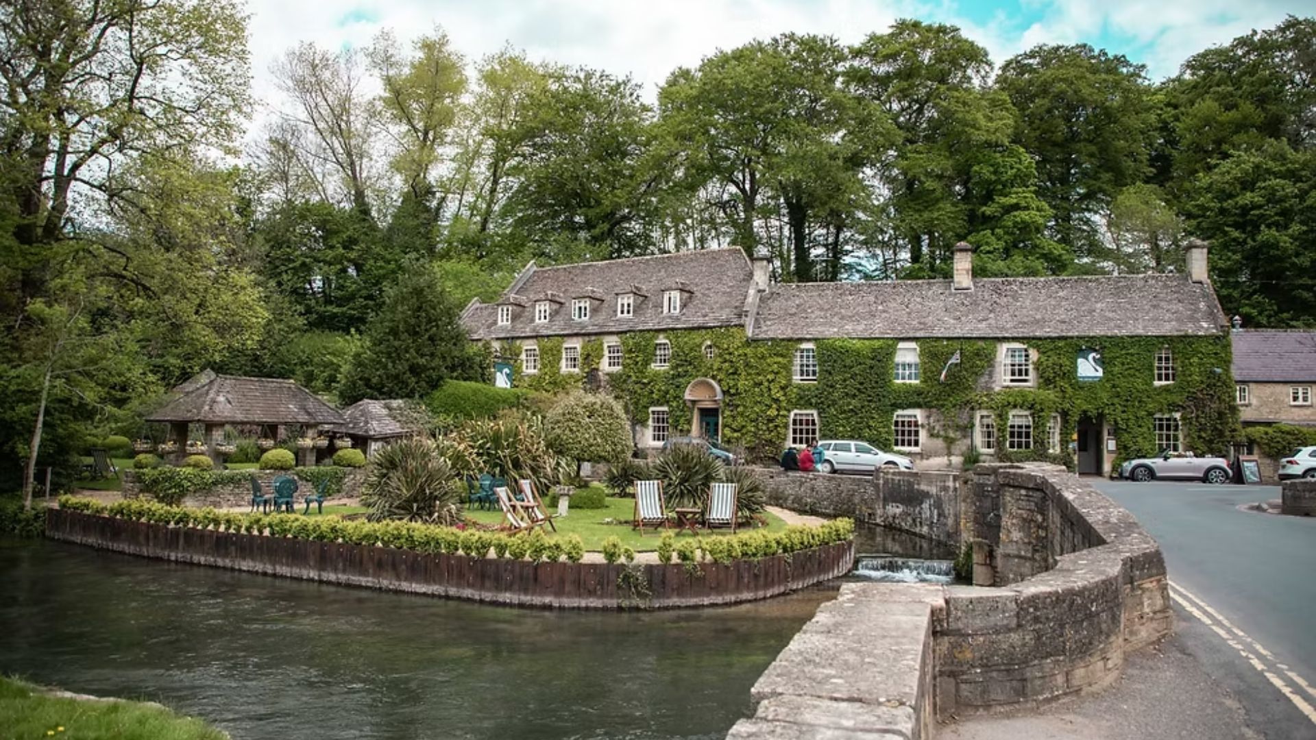 A river flows through a quaint small town, surrounded by trees and buildings, reflecting a peaceful atmosphere.