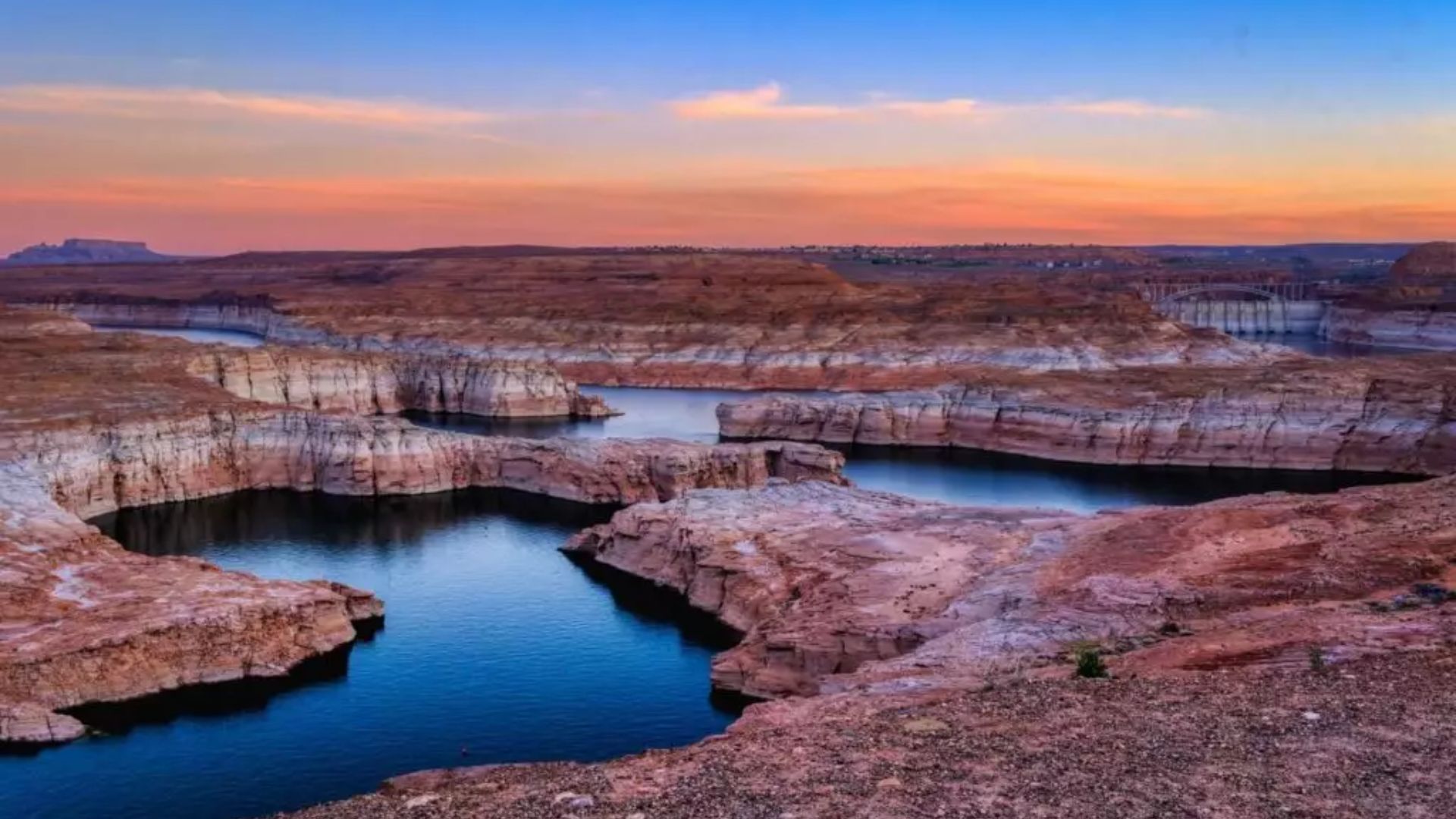 Lake Powell, a vast reservoir in the United States, is surrounded by stunning red rock formations and clear blue waters.