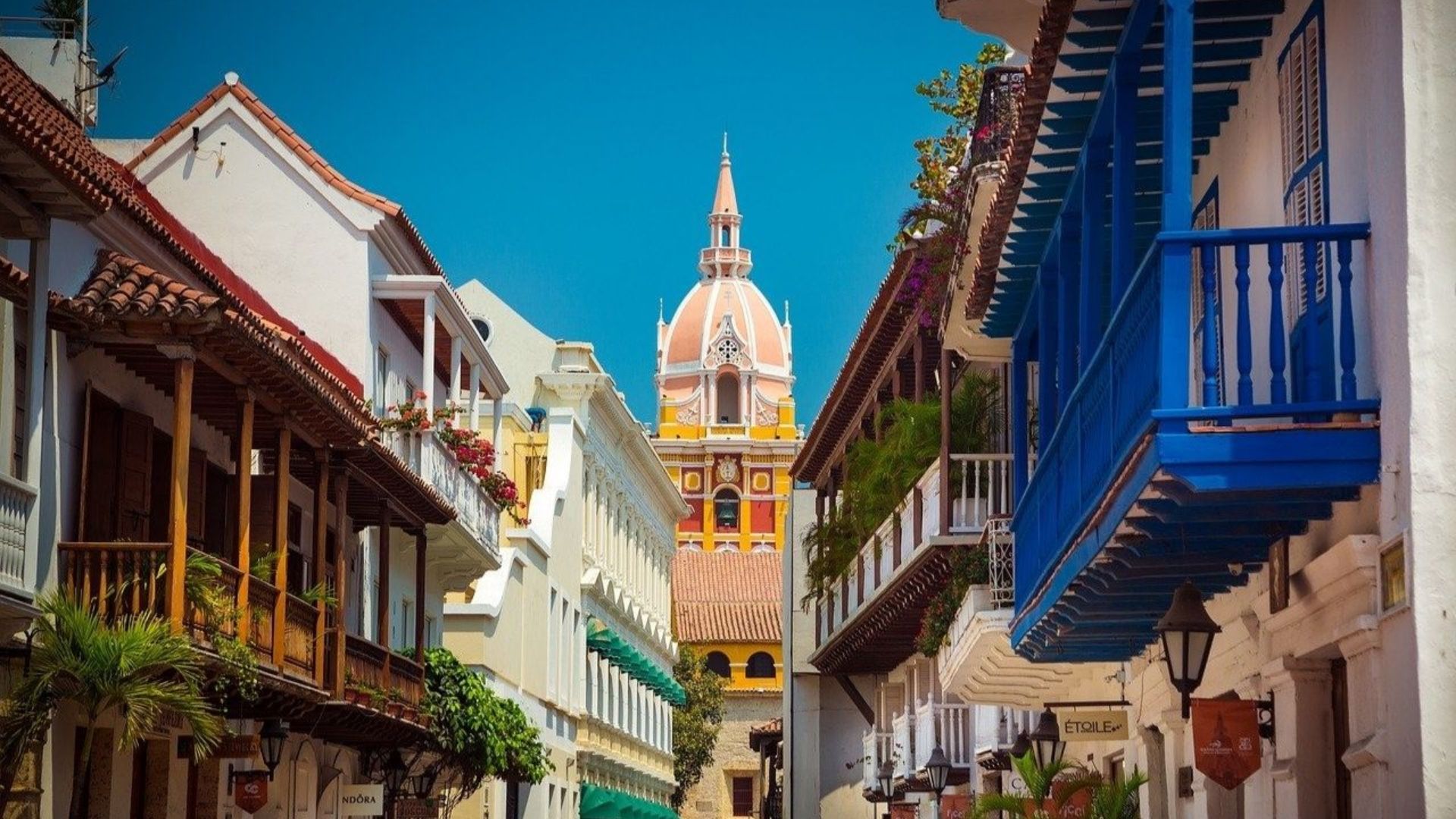 A narrow street lined with buildings, leading to a prominent church in the background.