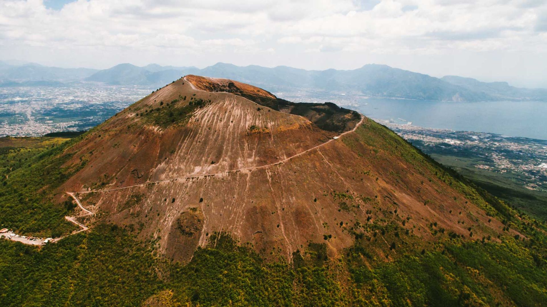 Aerial view of a mountain with a winding road traversing its peak, showcasing the landscape's natural beauty.