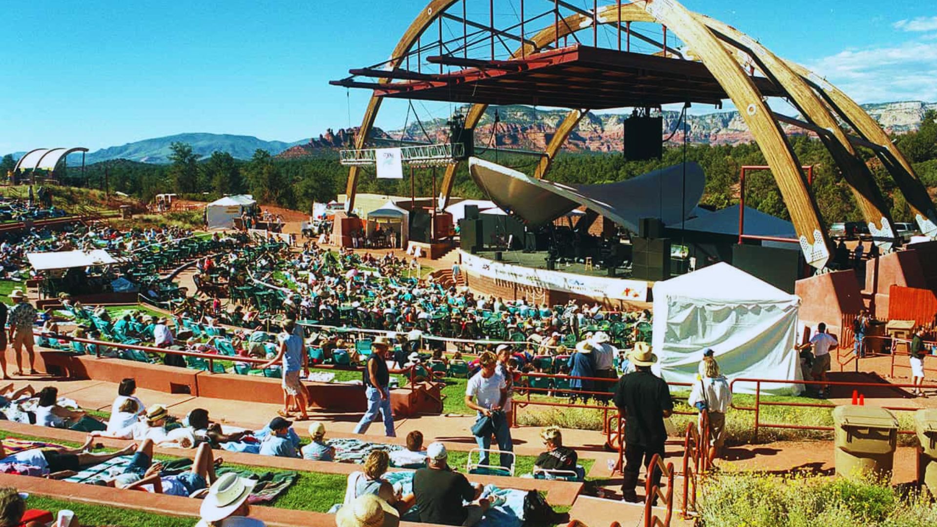 A large crowd enjoys a concert in the mountains, surrounded by scenic views and vibrant energy.