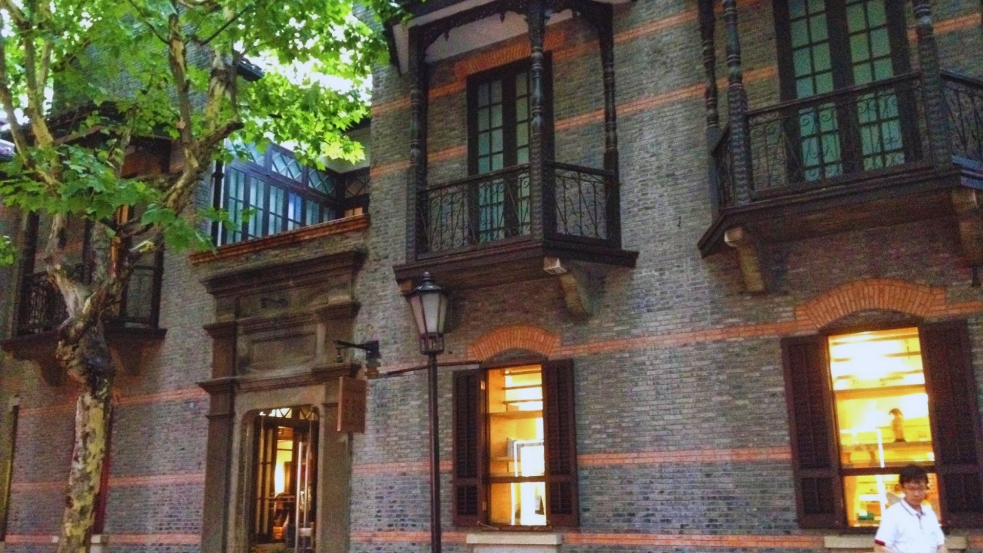 A man is seen walking past a brick building, capturing a moment of urban life on the street.