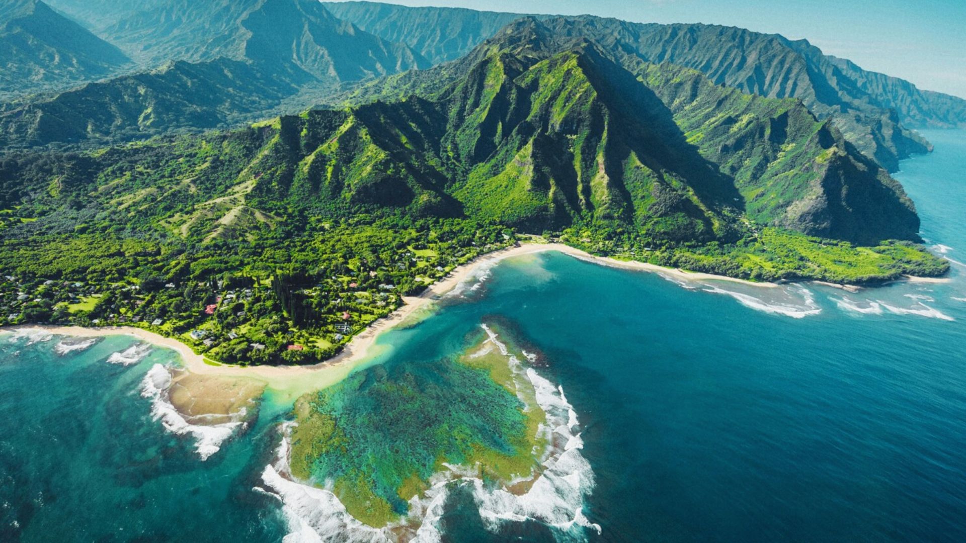 A stunning view of Kauai, Hawaii, showcasing its lush greenery and dramatic coastline under a clear blue sky.