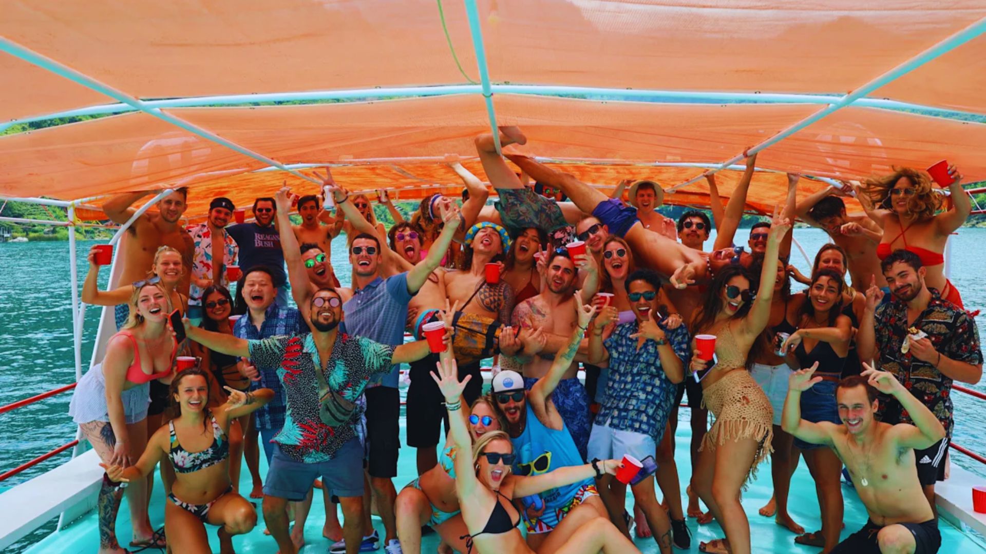 A group of people smiling and posing for a photo on a boat, surrounded by water and a clear sky.