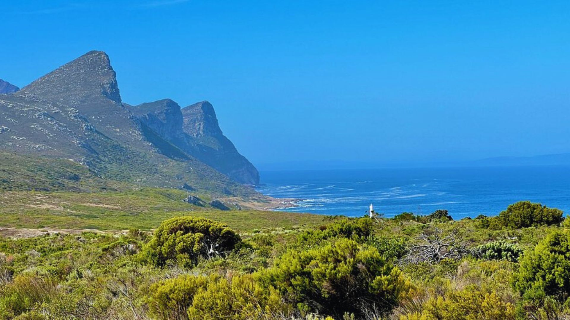 Scenic view of the Cape of Good Hope, showcasing rugged cliffs and the Atlantic Ocean under a clear blue sky.
