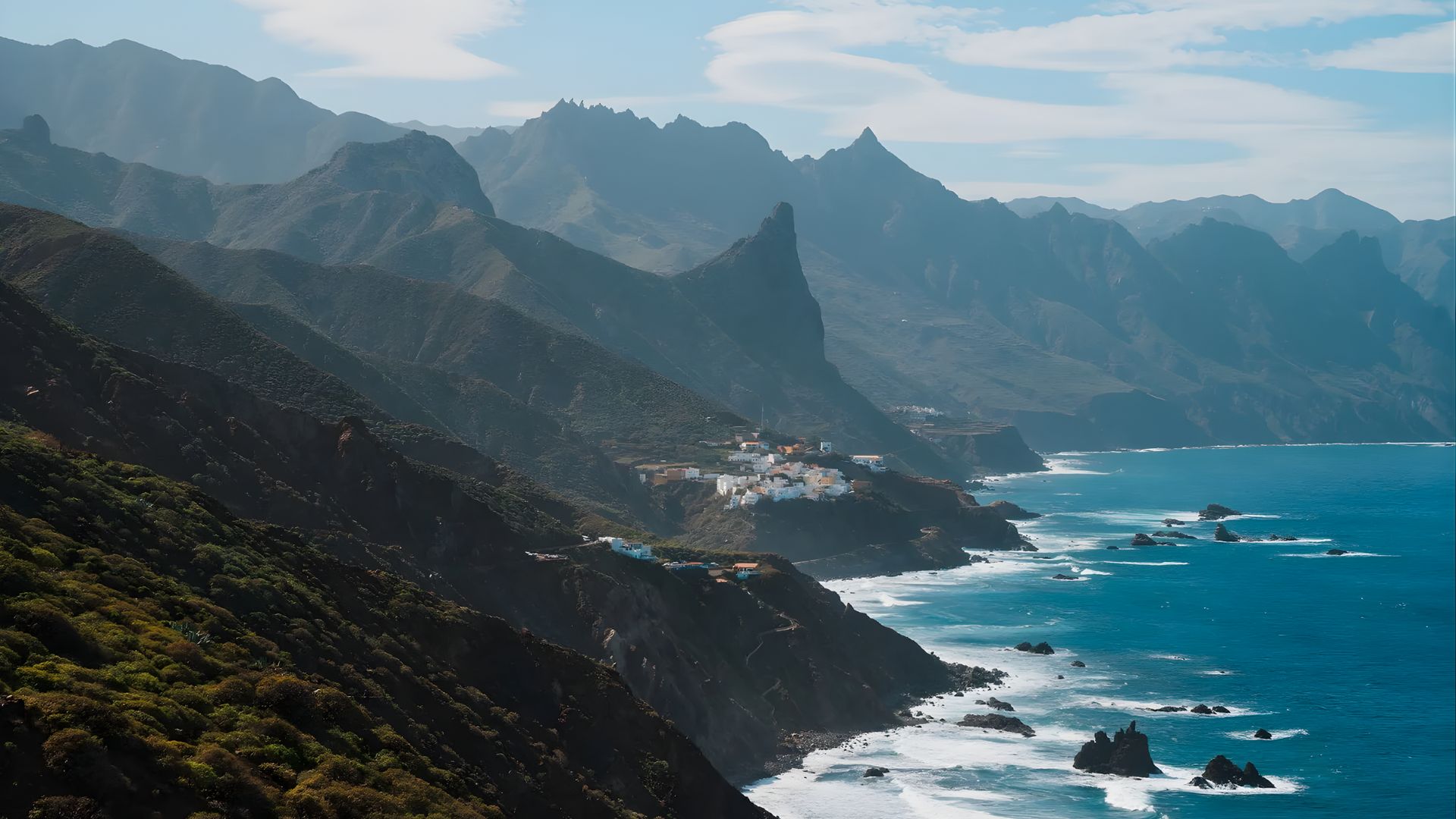 Coastal landscape of the Canary Islands, featuring dramatic cliffs and vibrant ocean waves under a clear sky.