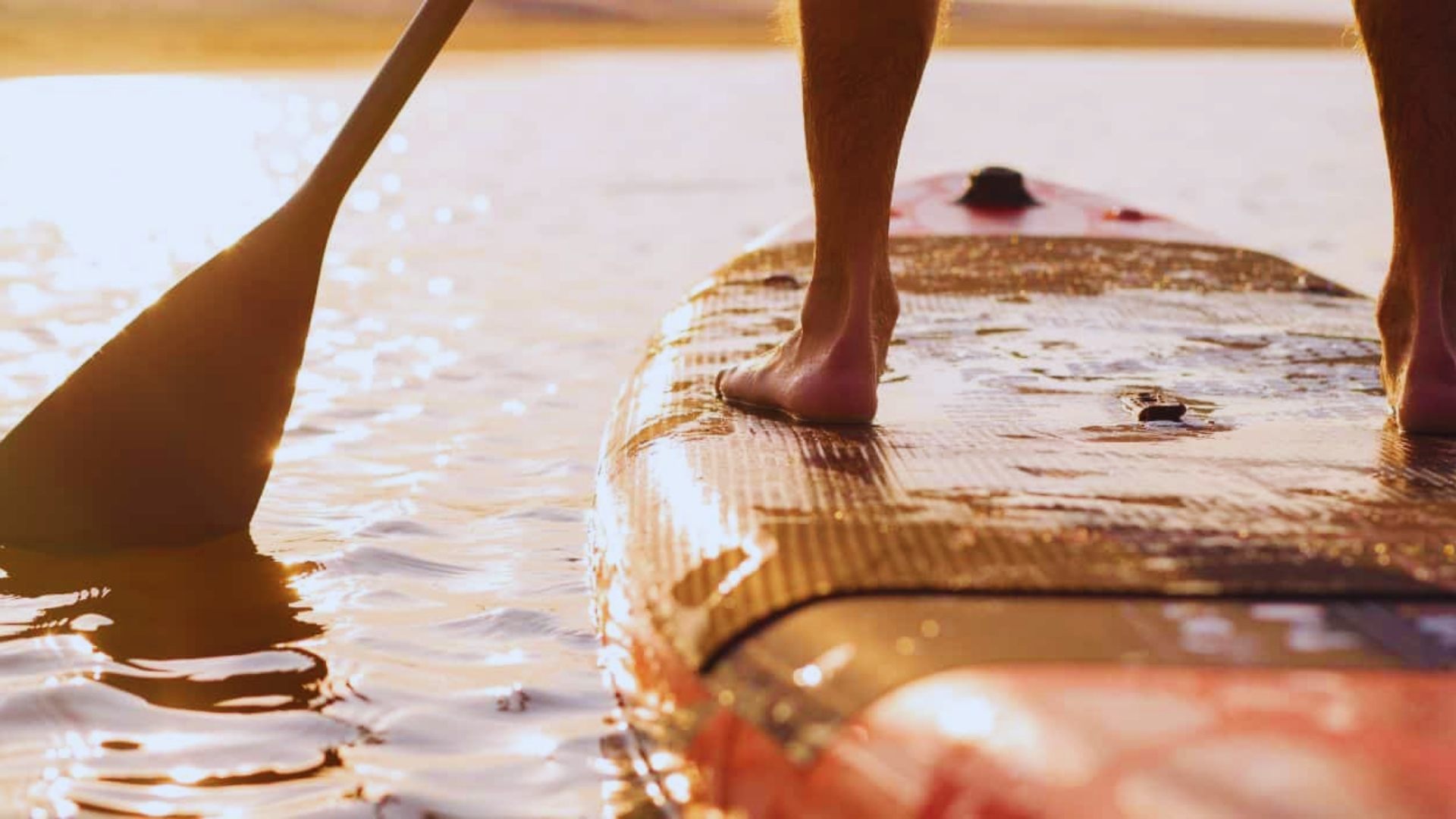 Individual on a paddle board, surrounded by water, enjoying a sunny day outdoors.
