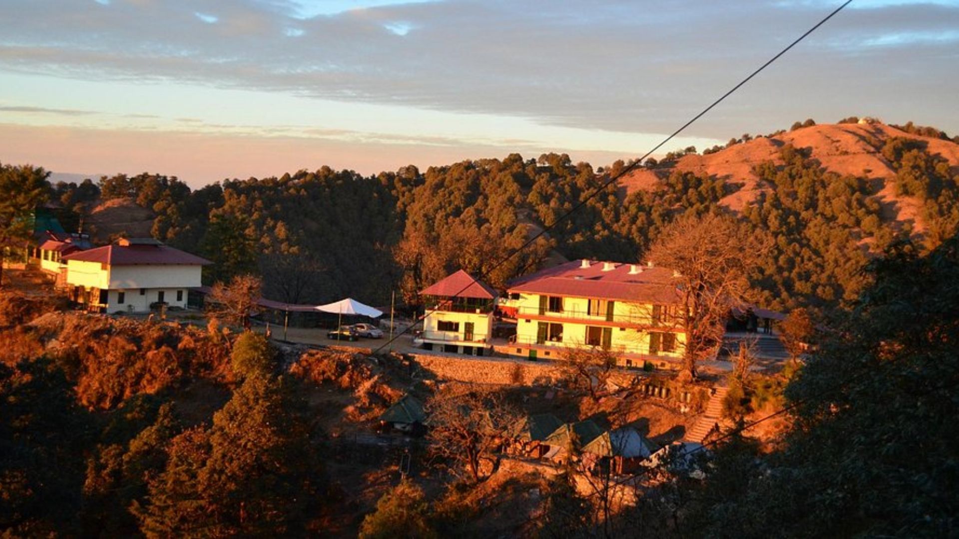 A scenic view of a house atop a hill, featuring a cable car traveling up the slope.