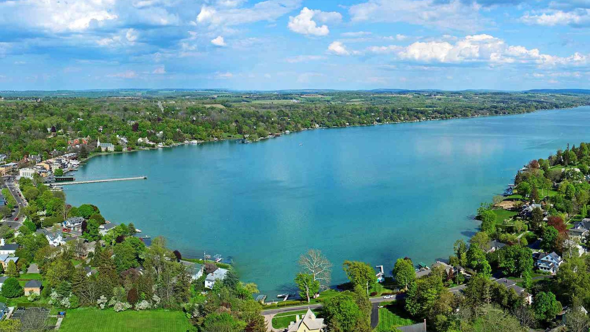 Aerial view of a serene lake surrounded by a picturesque town, showcasing the natural and urban landscape.