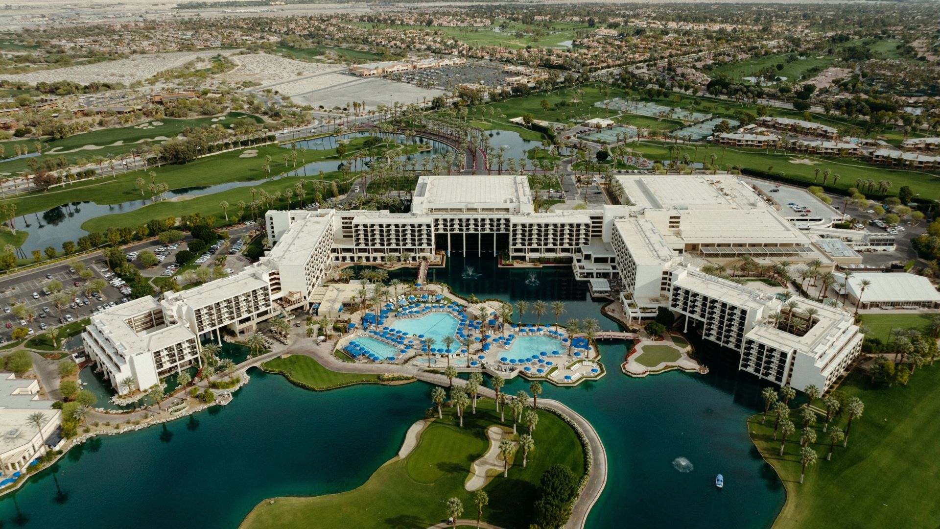 A resort situated in the center of a lush green golf course, surrounded by manicured fairways and scenic views.