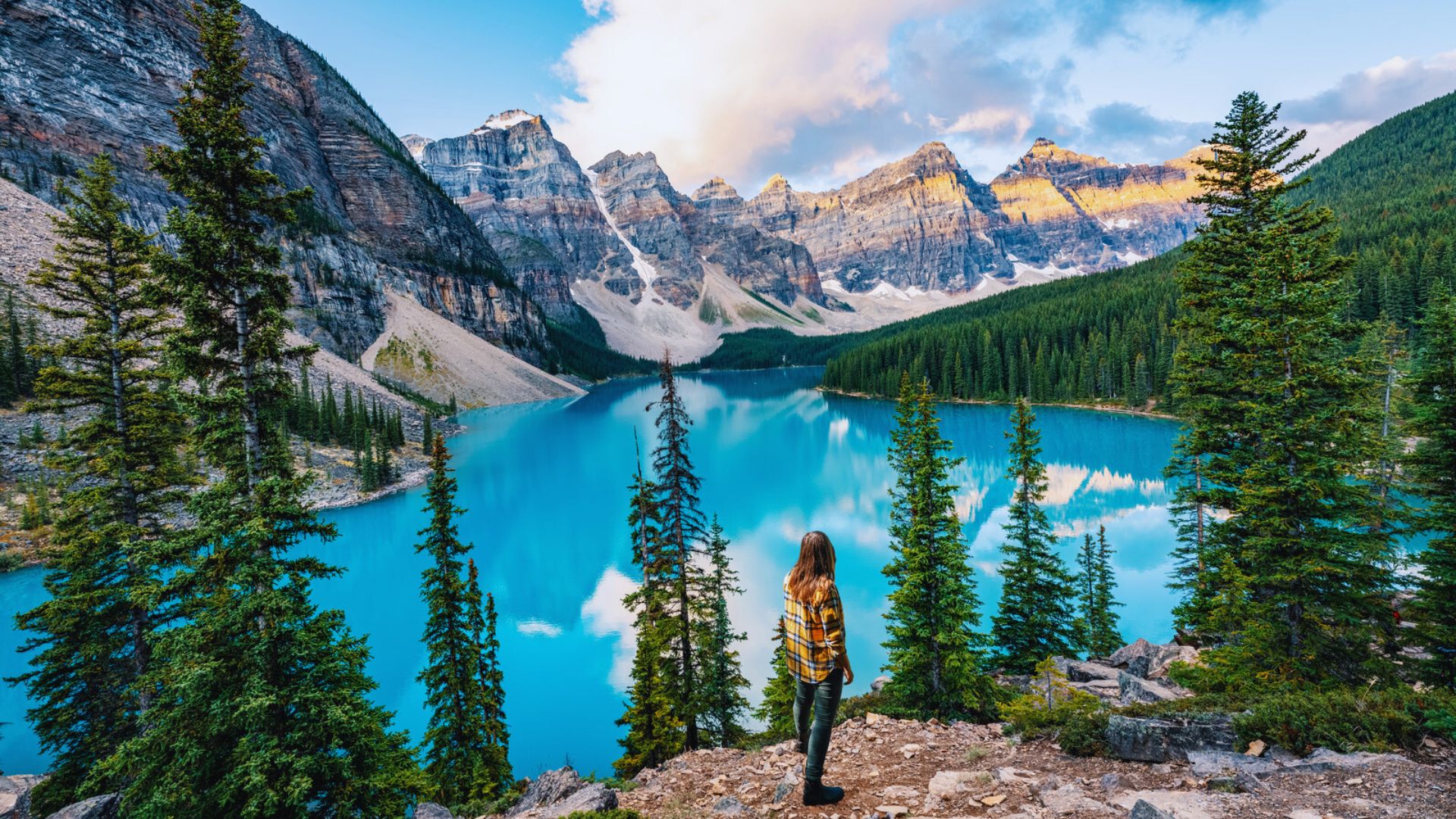 A cozy cabin nestled in the mountains, with lush trees and a peaceful lake nearby.