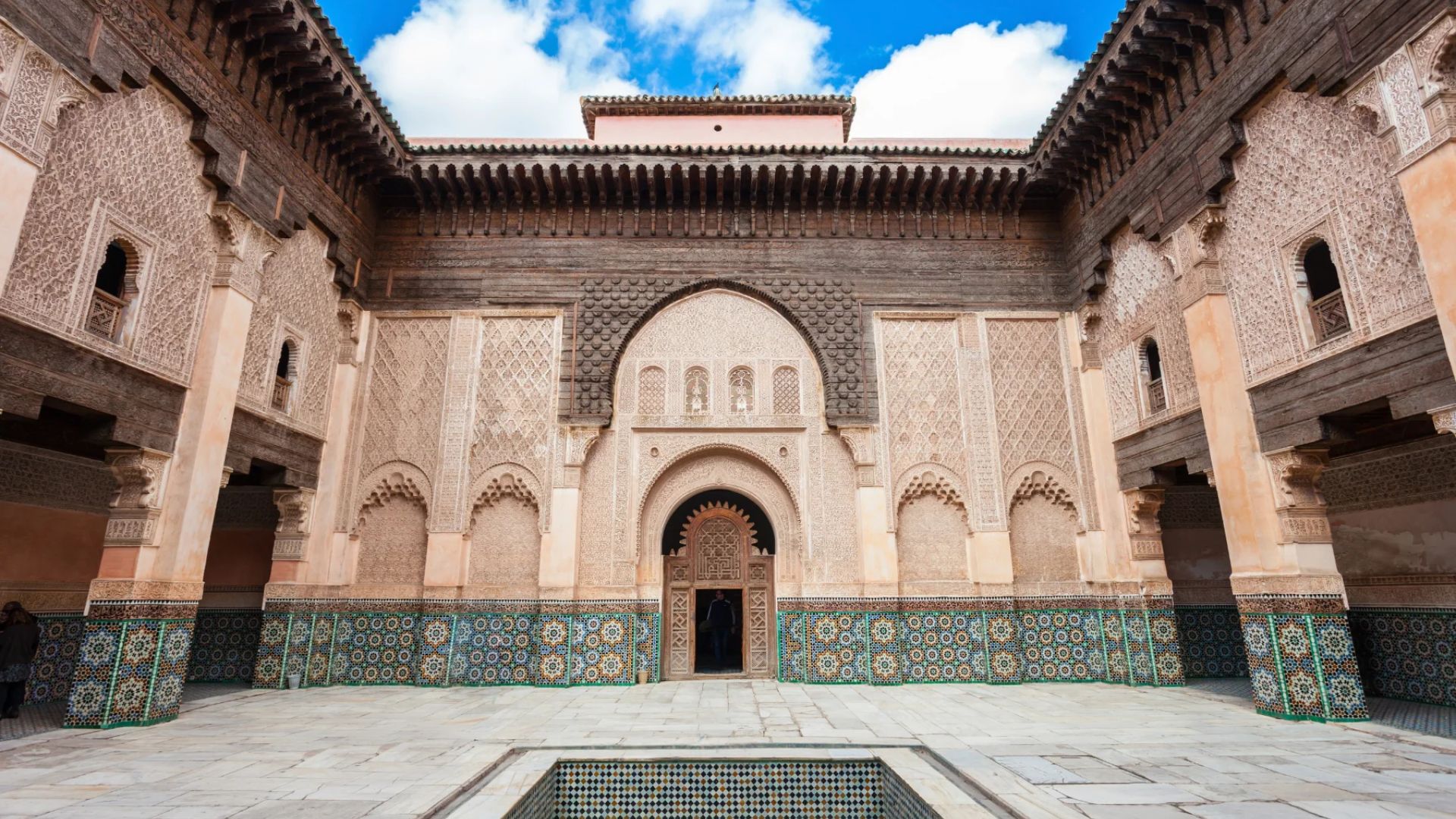 The courtyard of the royal palace in Marrakesh, Morocco, featuring intricate tile work and lush greenery.