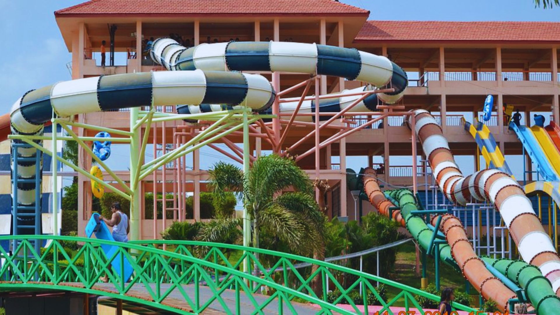 A vibrant water park featuring a large slide and a colorful slide, with families enjoying the attractions.
