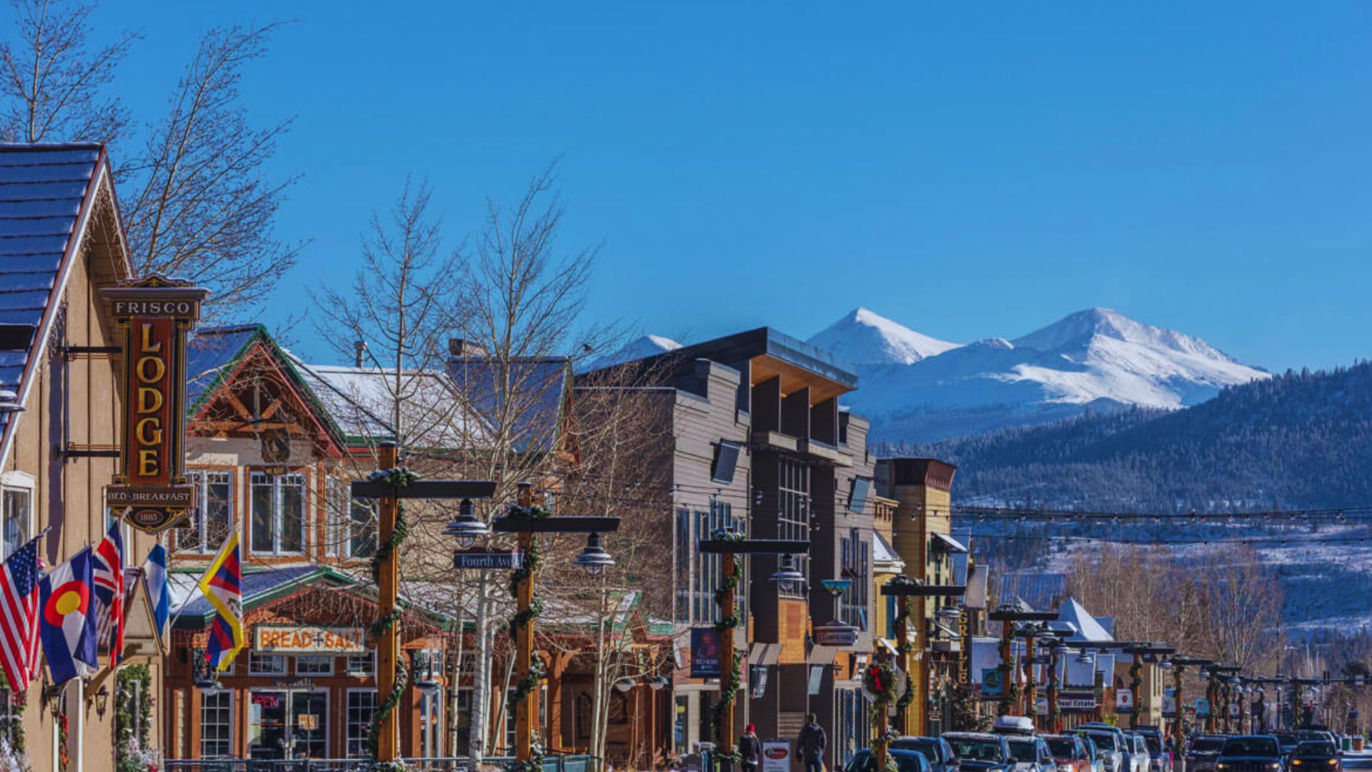 A city street with snow-covered mountains rising majestically in the background, creating a picturesque winter scene.