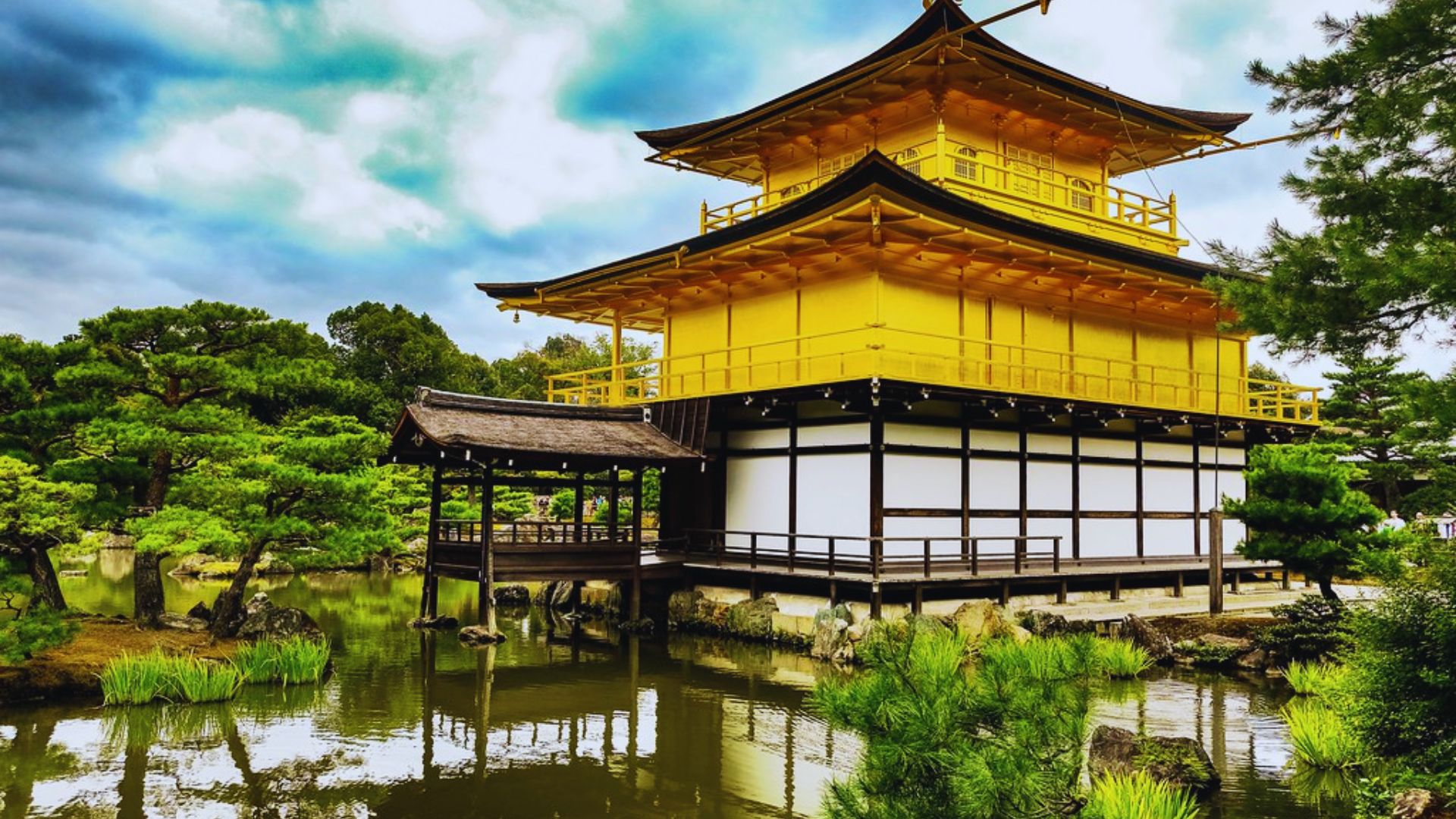 A yellow pagoda is situated atop a serene pond, reflecting its vibrant color in the water below.