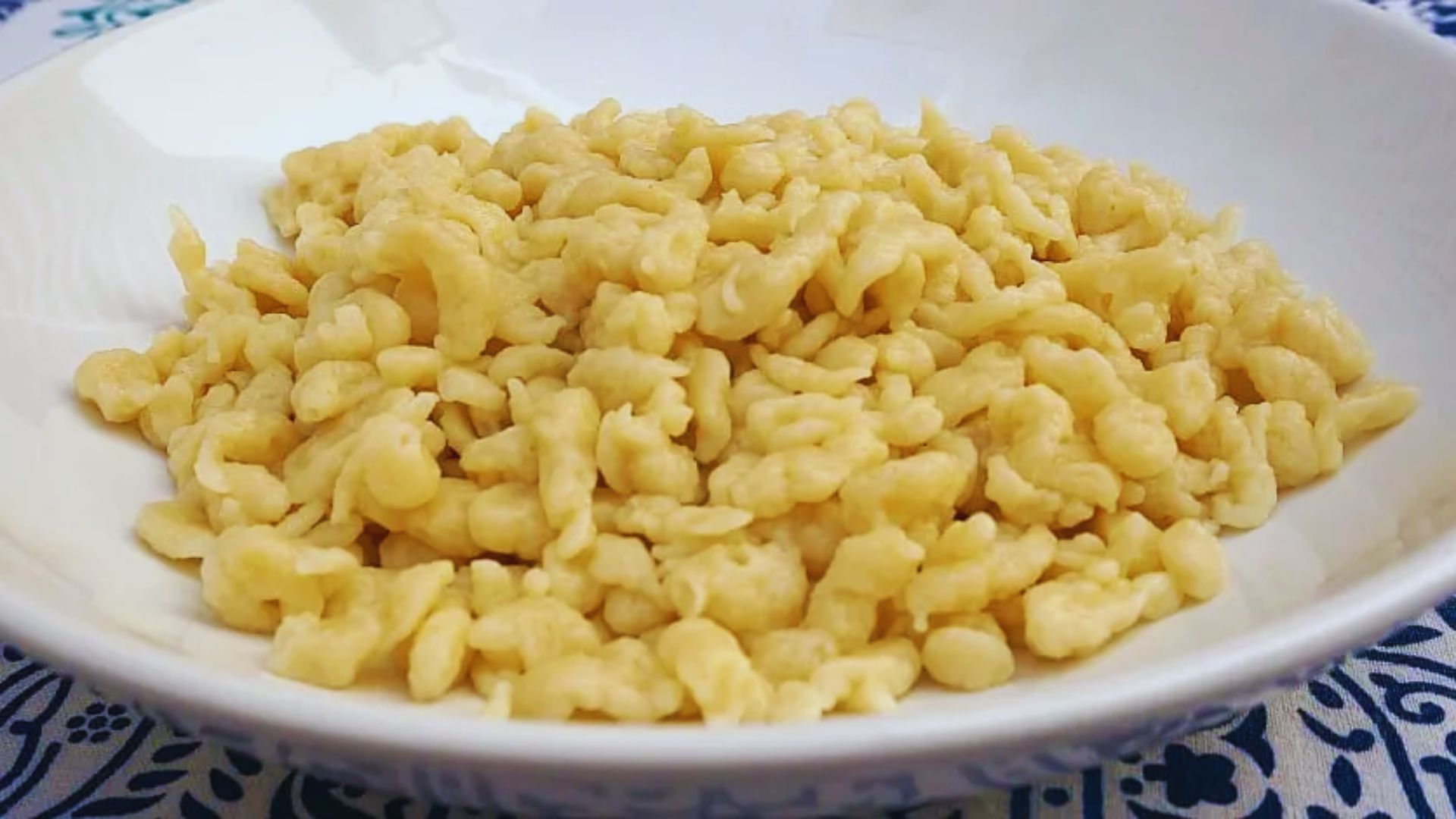 A bowl of macaroni featuring a blue and white patterned design, filled with pasta and ready to serve.